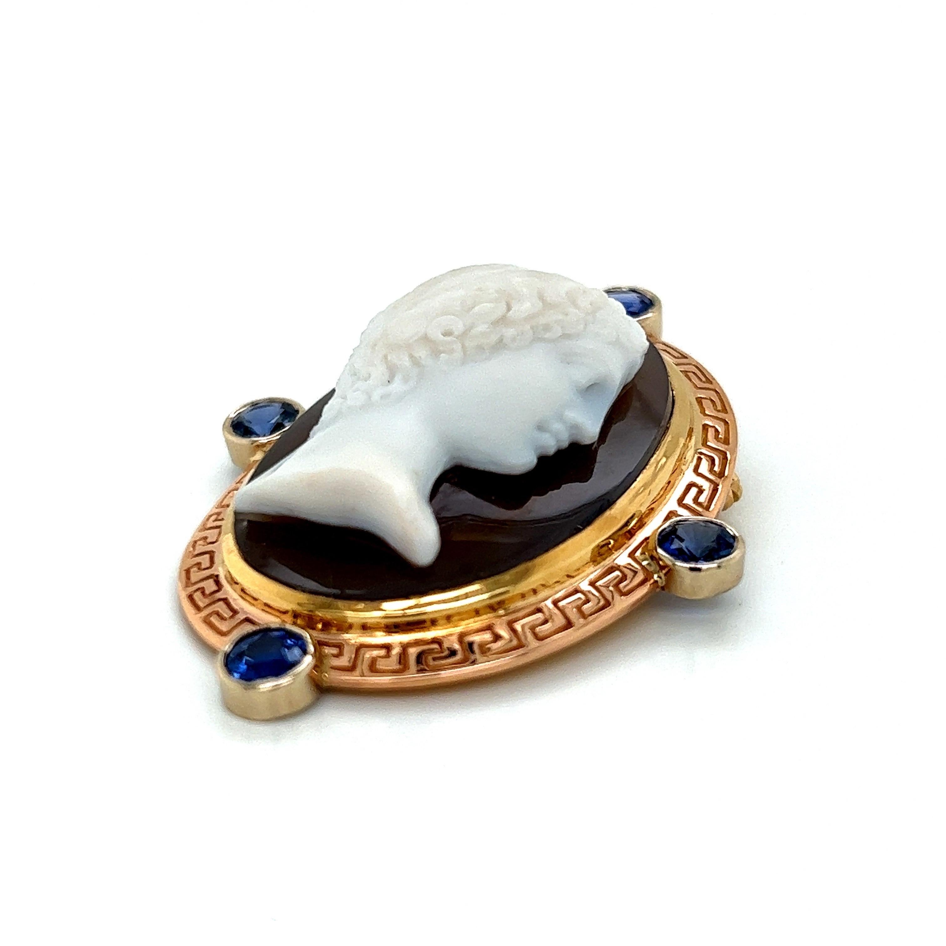 Brooch Pin with Antique Cameo of a Woman Set in 18k Yellow, White And Rose Gold Greek Key Bezel With approximately 2.5tct Of 5mm Faceted Round Blue Sapphires.

Pin measures 48.67mm x 38.62mm