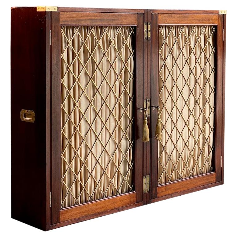 Magnificent 19th century military Campaign mahogany folding bookcase circa 1840, fitted with two wire mesh doors with silk pleated curtains enclosing four shelves, both doors with original working locks, brass bound with carry handles to sides,