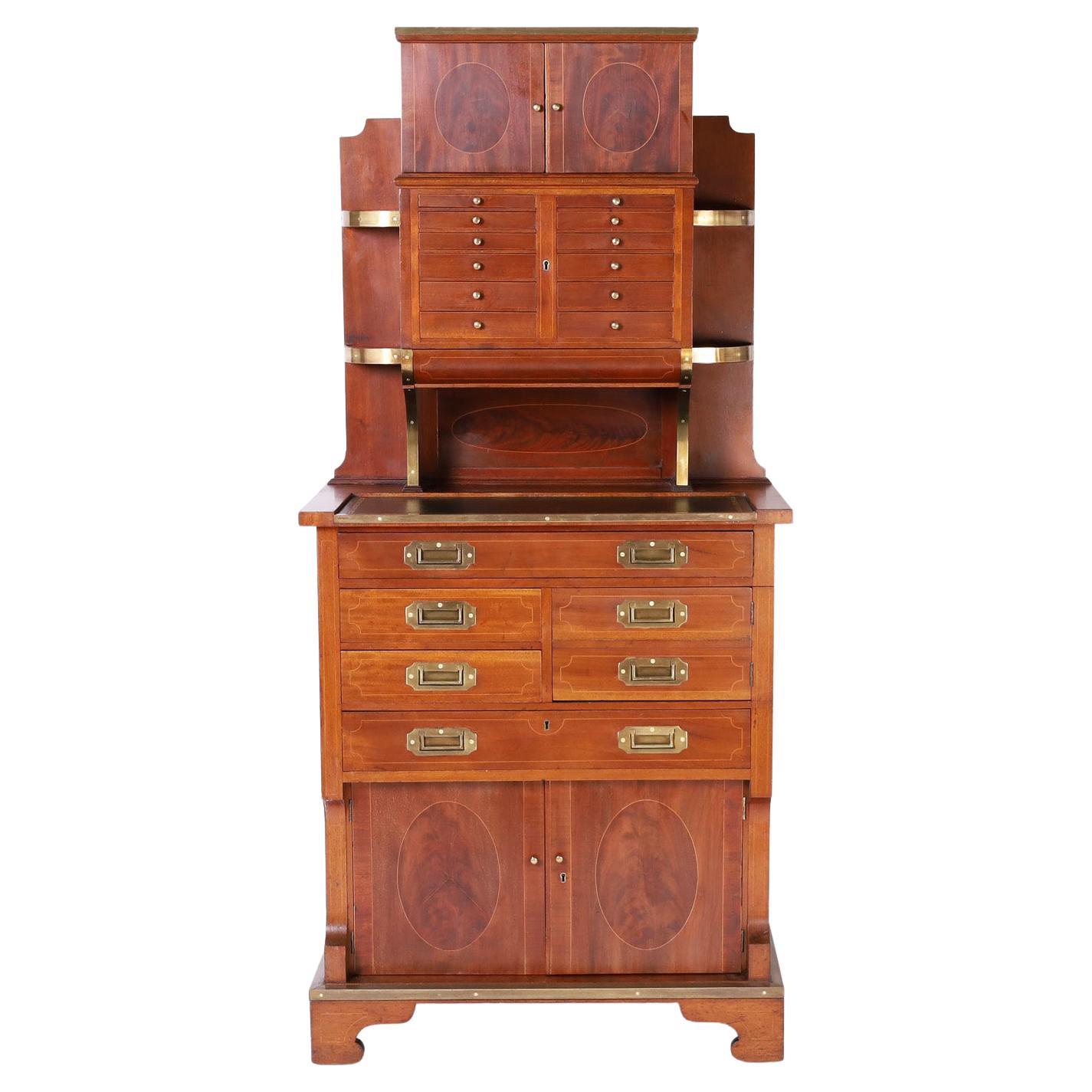 Edwardian Captain's upright secretary crafted in mahogany with inlaid ovals on the cabinet door fronts, brass campaign hardware, tooled leather writing surface, plenty of drawer storage and set on classic bracket feet.