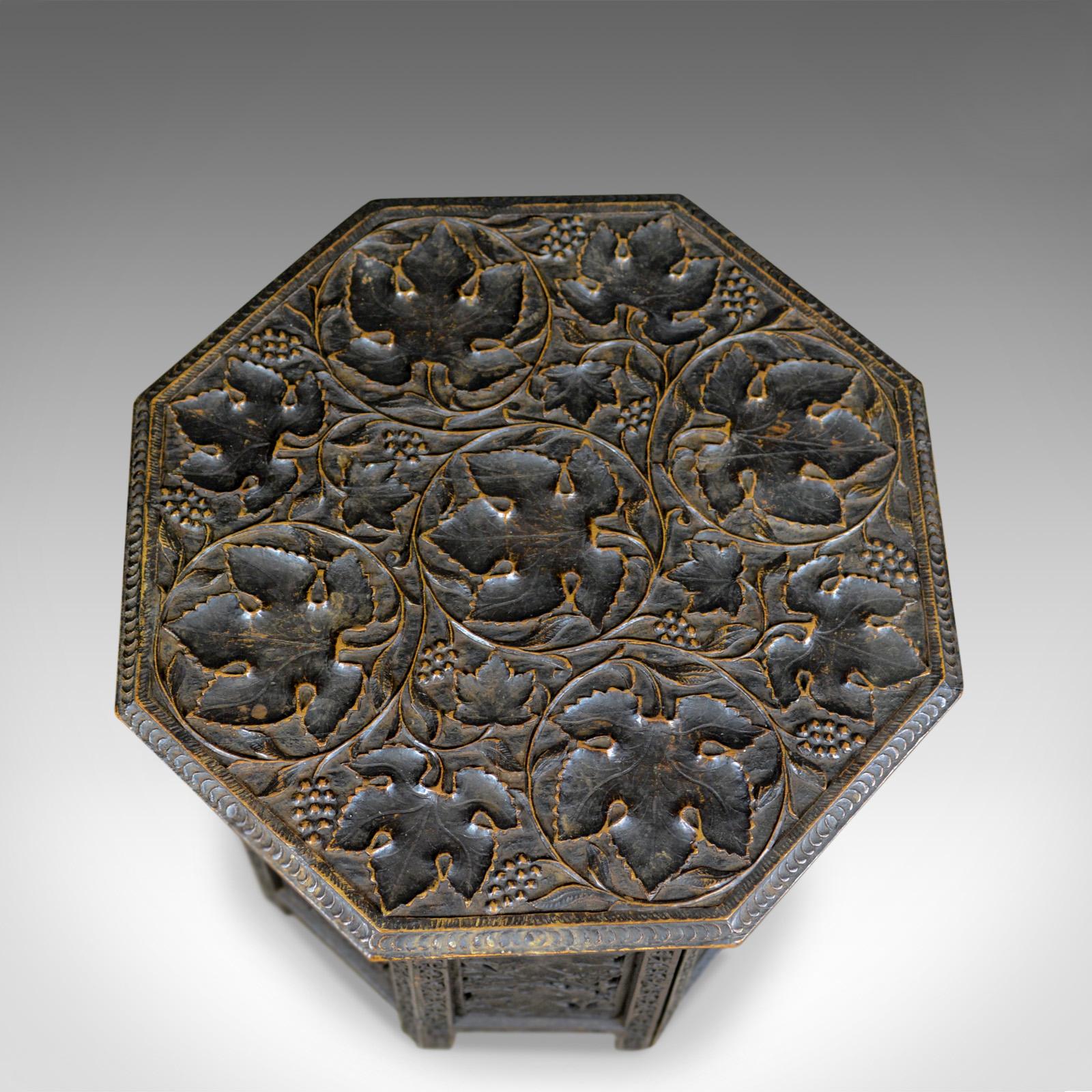 This is an antique campaign table, a beautifully carved, Asian, teak side table dating to the turn of the century, circa 1900.

Profusely carved in deep relief
Fruit and foliate detail to the octagonal top
Pierced detailing to panel