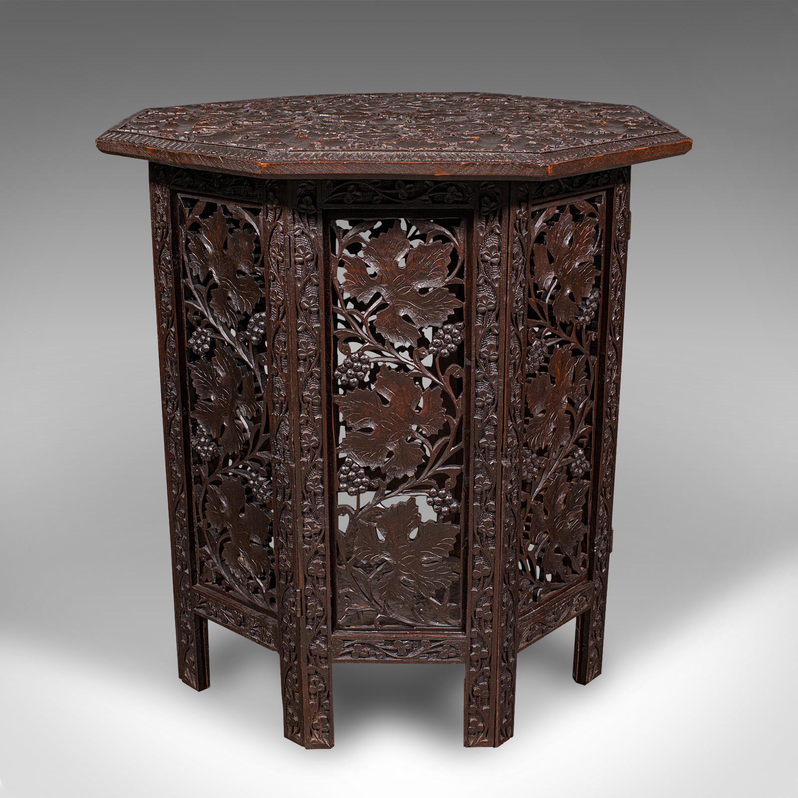 This is an antique campaign tea table. An Anglo-Indian, relief carved teak folding table of octagonal form, dating to the late Victorian period, circa 1900. Profusely detailed and highly practical, this charming piece offers elegant utility with