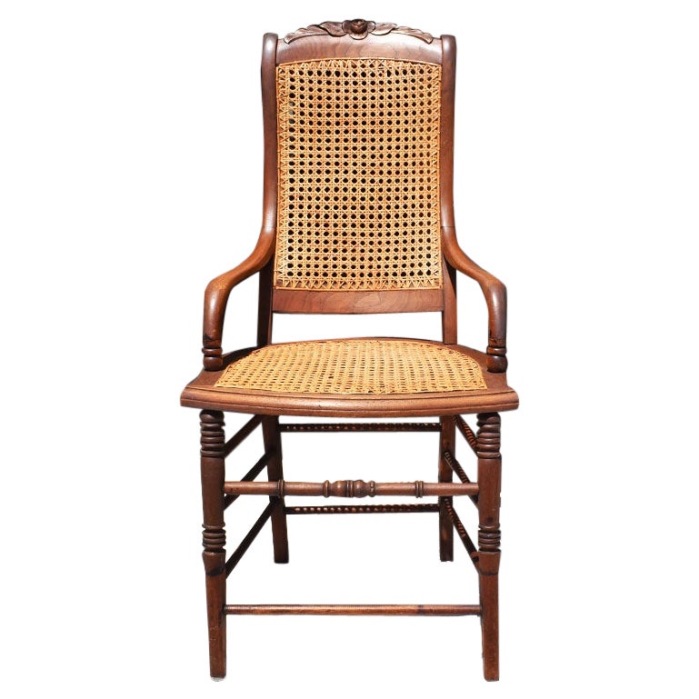 Silla auxiliar antigua de brazo de caña y madera tallada con detalle de rosa