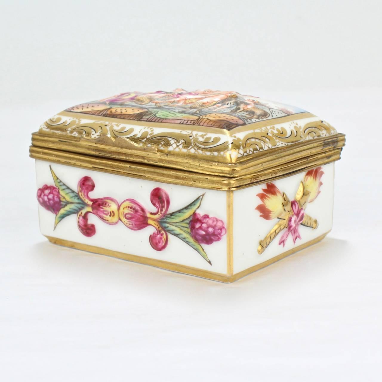 A fine, antique Capodimonte porcelain table snuff box in the Meissen style.

With a polychrome enamel Bacchanalian scene on the lid, neoclassical devices on the side panels, and a fine gilt bronze mount.

The base bears a blue underglaze 'N
