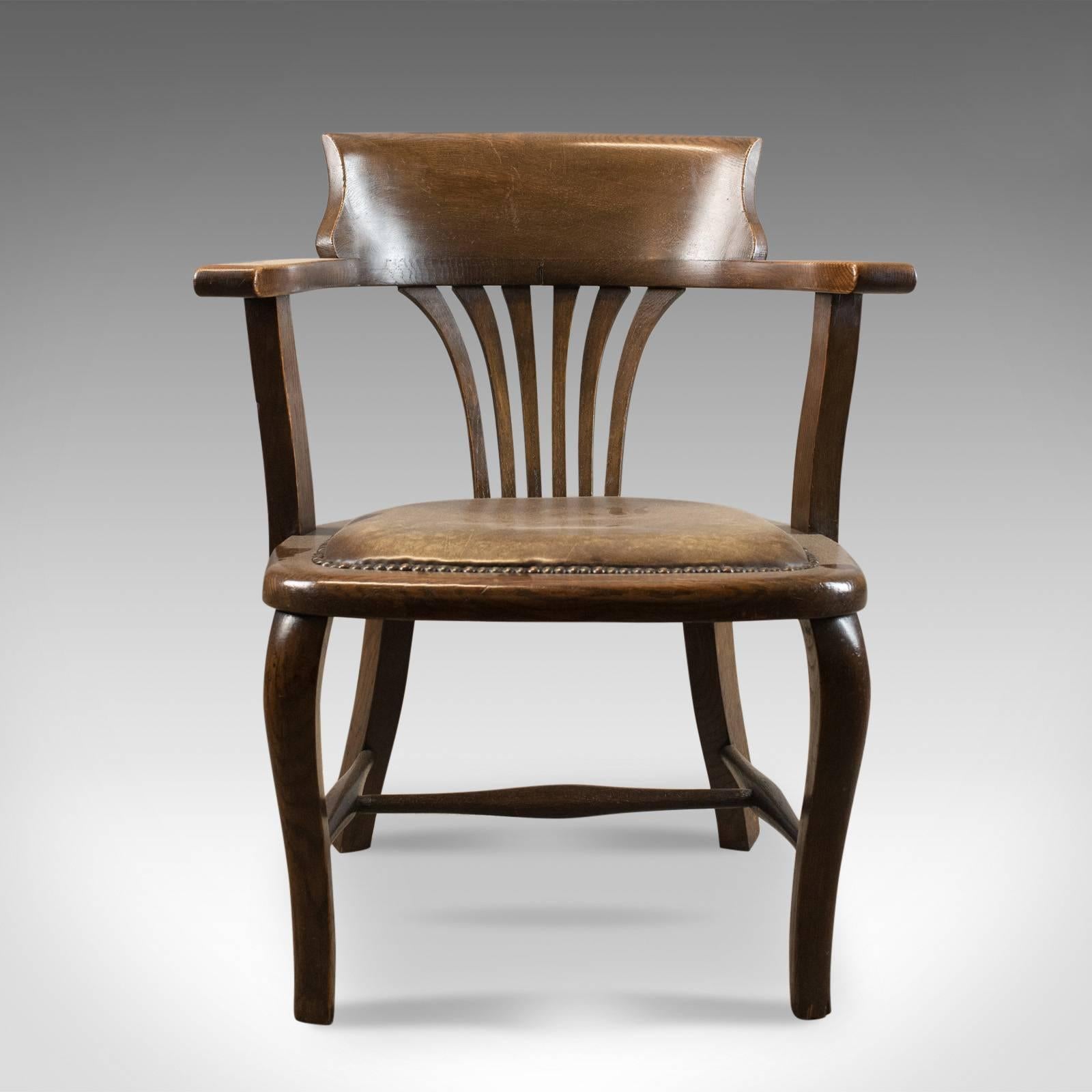 This is an antique Captain's chair, an English, oak bow-back with leather seat dating to the Edwardian period, circa 1910.

Crafted in English oak with good consistent color
Solidly made with desirable aged patina
Oblique cabriole legs to the