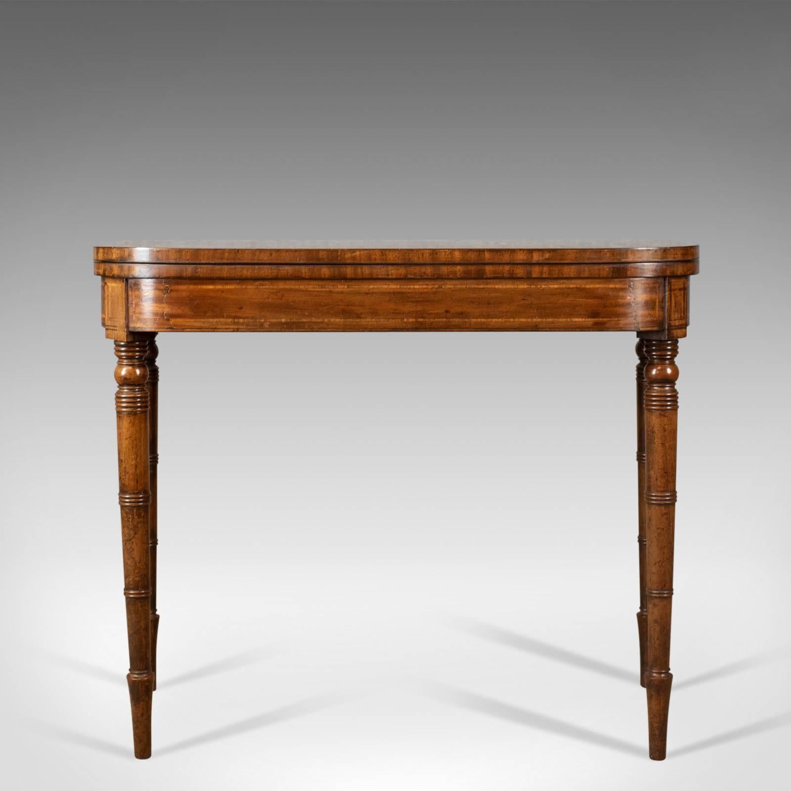 This is an antique card table, a late Georgian, English fold-over games table dating to circa 1820.

Super pale mahogany displaying grain interest
Good colour and a desirable aged patina 
Finely crossbanded, complimentary border
Inlaid,