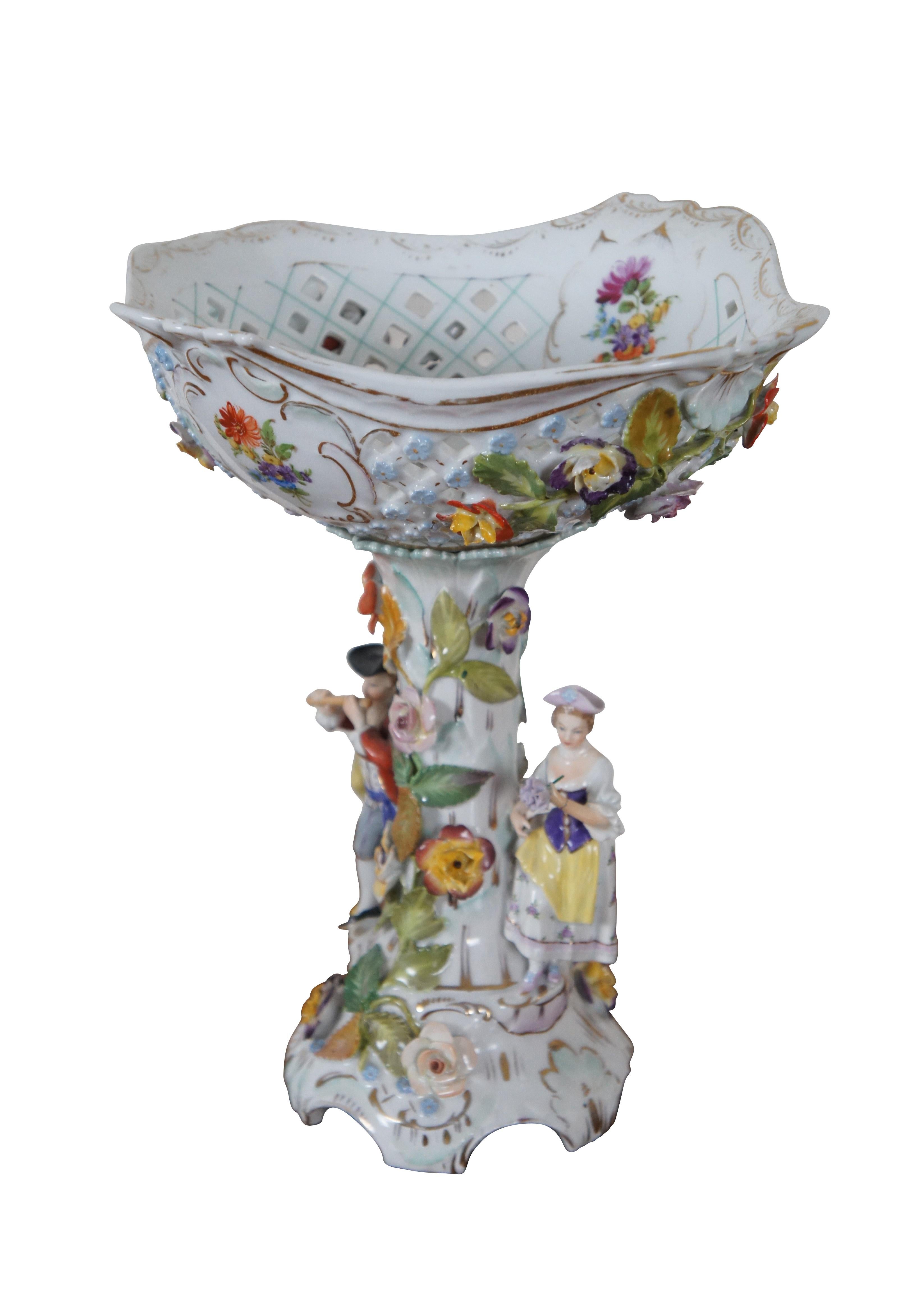 Antique Carl Thieme German Dresden centerpiece compote.  Made of porcelain featuring high relief footed base and reticulated / pierced scalloped bowl with two colonial figures, a man playing a flute and a lady holding flowers.  Circa 1902-1920.

The