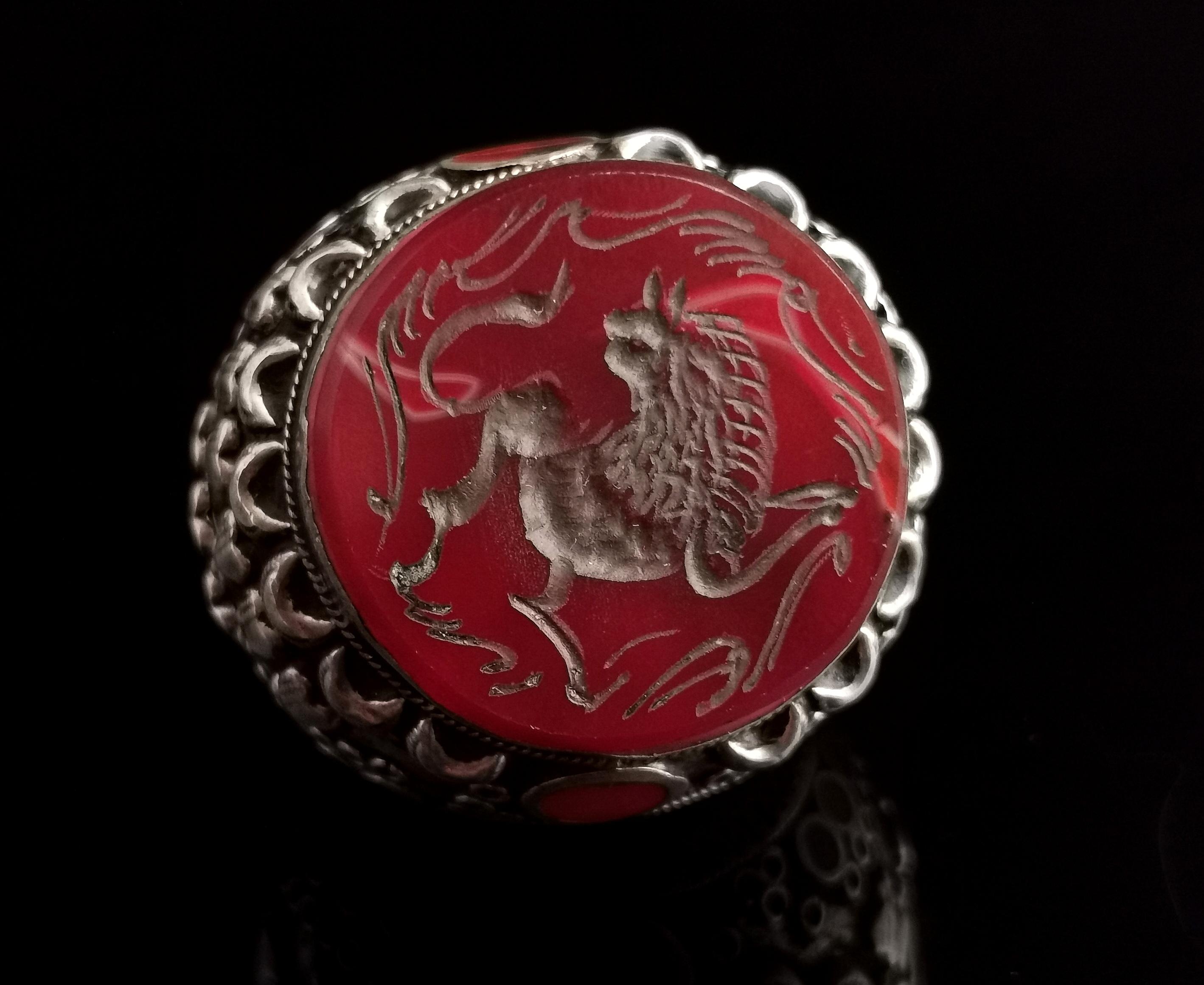 An impressive antique Middle Eastern intaglio ring.

A true statement piece, this is a huge and heavy gents bombe style ring set with a large carved Carnelian intaglio set to the front.

The Carnelian is carved with a primitive mythical creature,