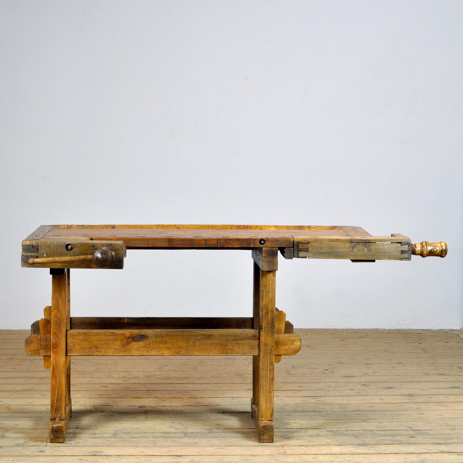 This antique workbench has two built-in wooden vise screws and a recessed tray where the carpenter would put his tools. It was manufactured around 1910. Made from oak. Beautiful patina after years of use. The workbench has been treated for woodworm,