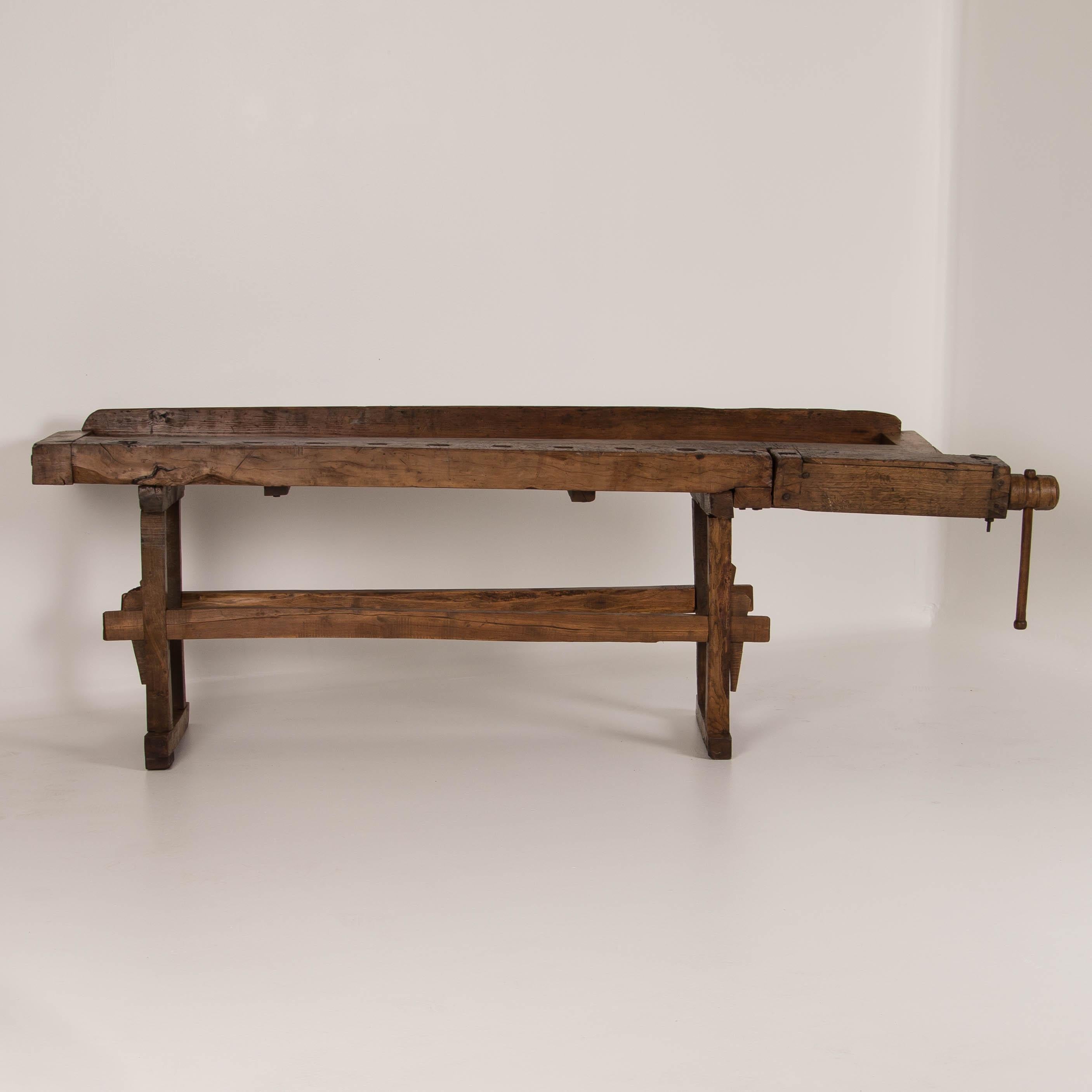 Beautiful antique carpenters workbench, bearing an incredible patina after years of traditional use, circa 1900. It has a single wood handled vice with continuous narrow table top and comes with a traditional trestle base that allows it to be