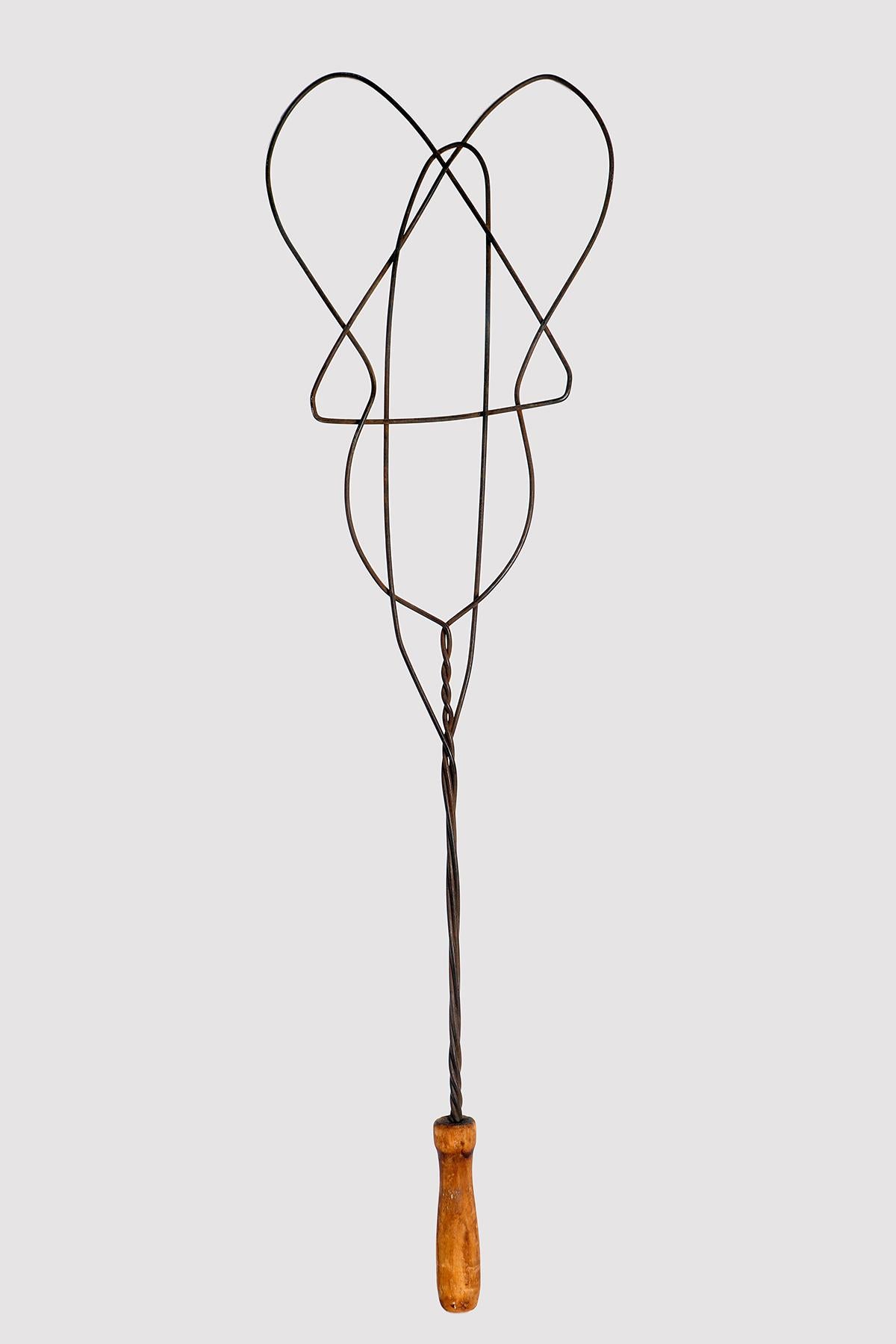 Antique carpet beater, to remove dust from carpets, in the shape of a guitar in heavy twisted metal wire woven into a honeycomb, to obtain greater resistance. The handle is made of fruit wood. United Kingdom, dating back to the late 1800s.