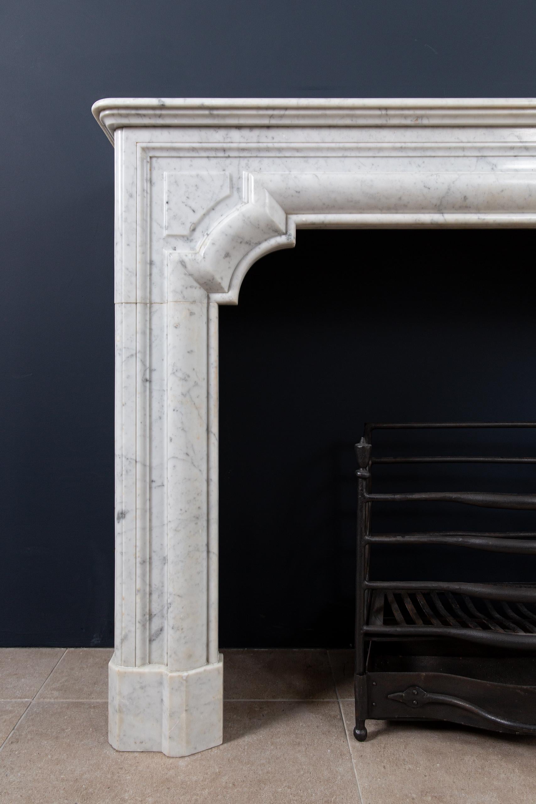 Une belle cheminée française de style antique Bolection en marbre de Carrara. Ce style de cheminées se caractérise par un bord de fraisage rond et continu. Cela continue depuis les consoles jusqu'à l'avant. L'épaisseur du marbre donne à cette