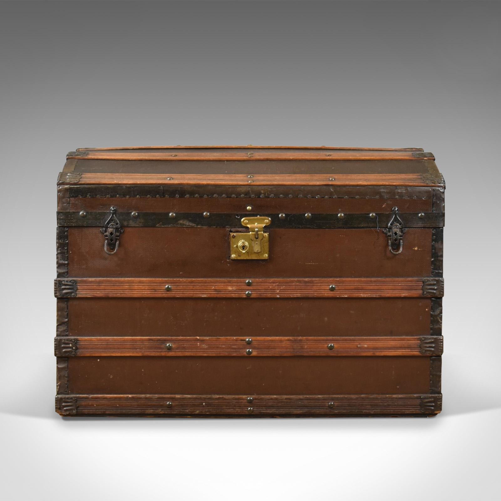 This is an antique carriage chest, an English, Victorian dome topped trunk dating to the late 19th century, circa 1890.

Robust outer construction strapped with wooden lathes
Flip clasps to the front, clasp operational, key absent
Metal bound