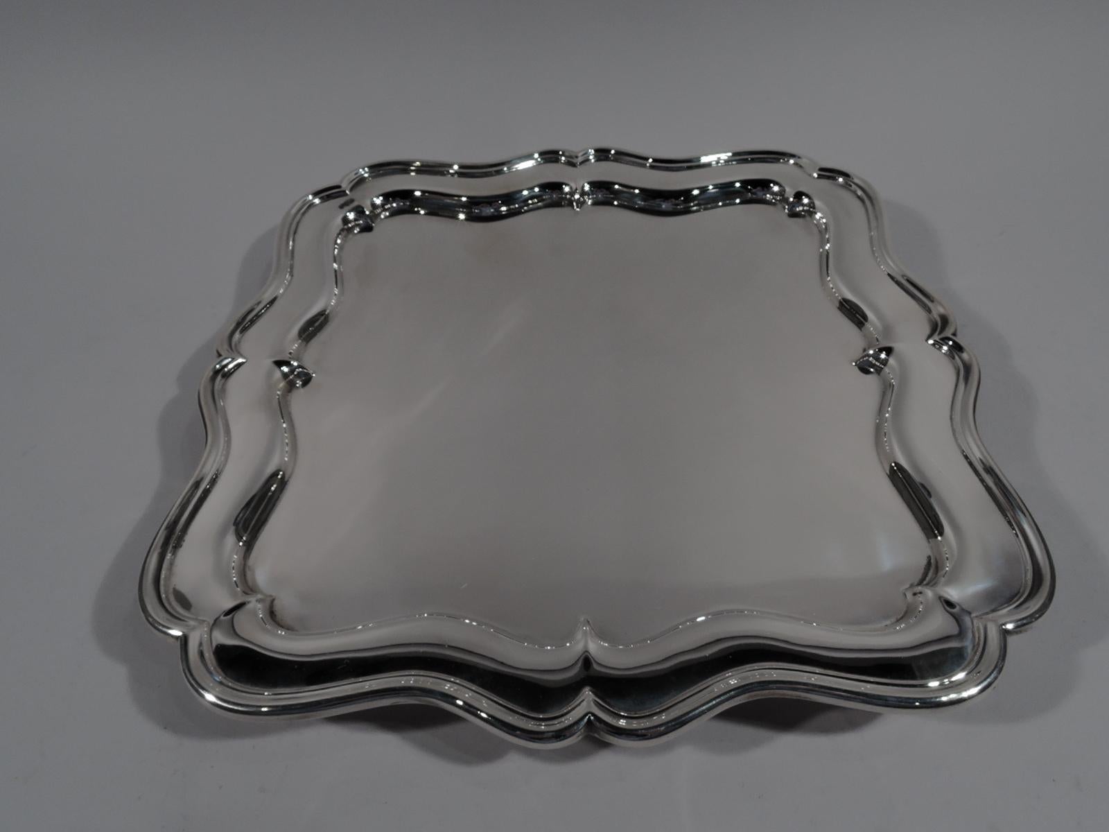 George V sterling silver footed tray. Made by William Comyns in London in 1912. Four scrolled sides with well and molded rim. Corners double scroll as are corner supports. A fancy piece with nice heft. English marks and Cartier retailer’s stamp.