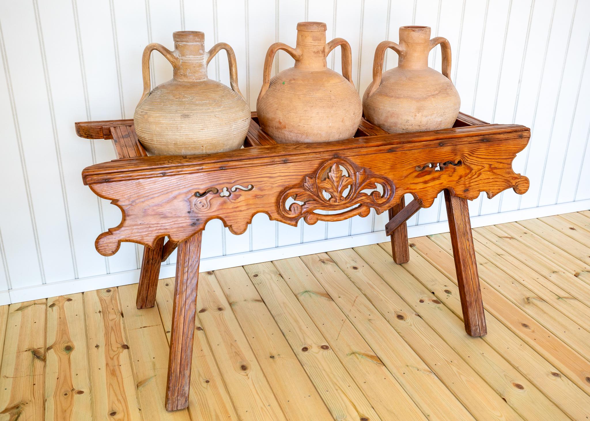 A strikingly attractive, extremely rare and wonderfully decorative carved oak amphora stand with three terracotta amphorae in lovely antique condition. Likely crafted in Spain in the early Twentieth Century, this superbly stylish beauty will add