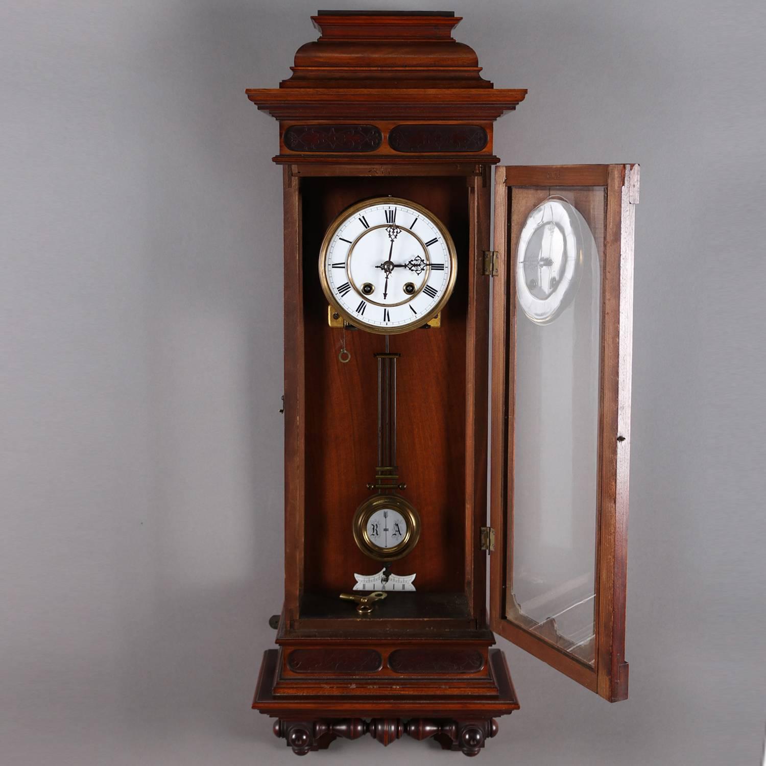 Antique carved walnut Vienna regulator wall clock features stepped crest with scroll decorated incised border above case with glass door framed in incised and gilt bordering and opening to works with clock face having Roman numerals and adjustable