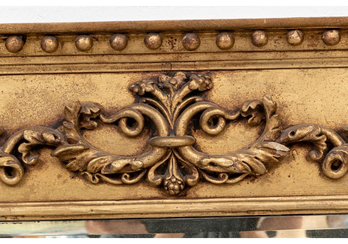 The three part beveled mirror with classic 19th c. details. The cornice with attached balls (a few missing on the left) and three projecting leafy column supports with rosettes on the top and bottoms. The frieze with raised shells flanking a center