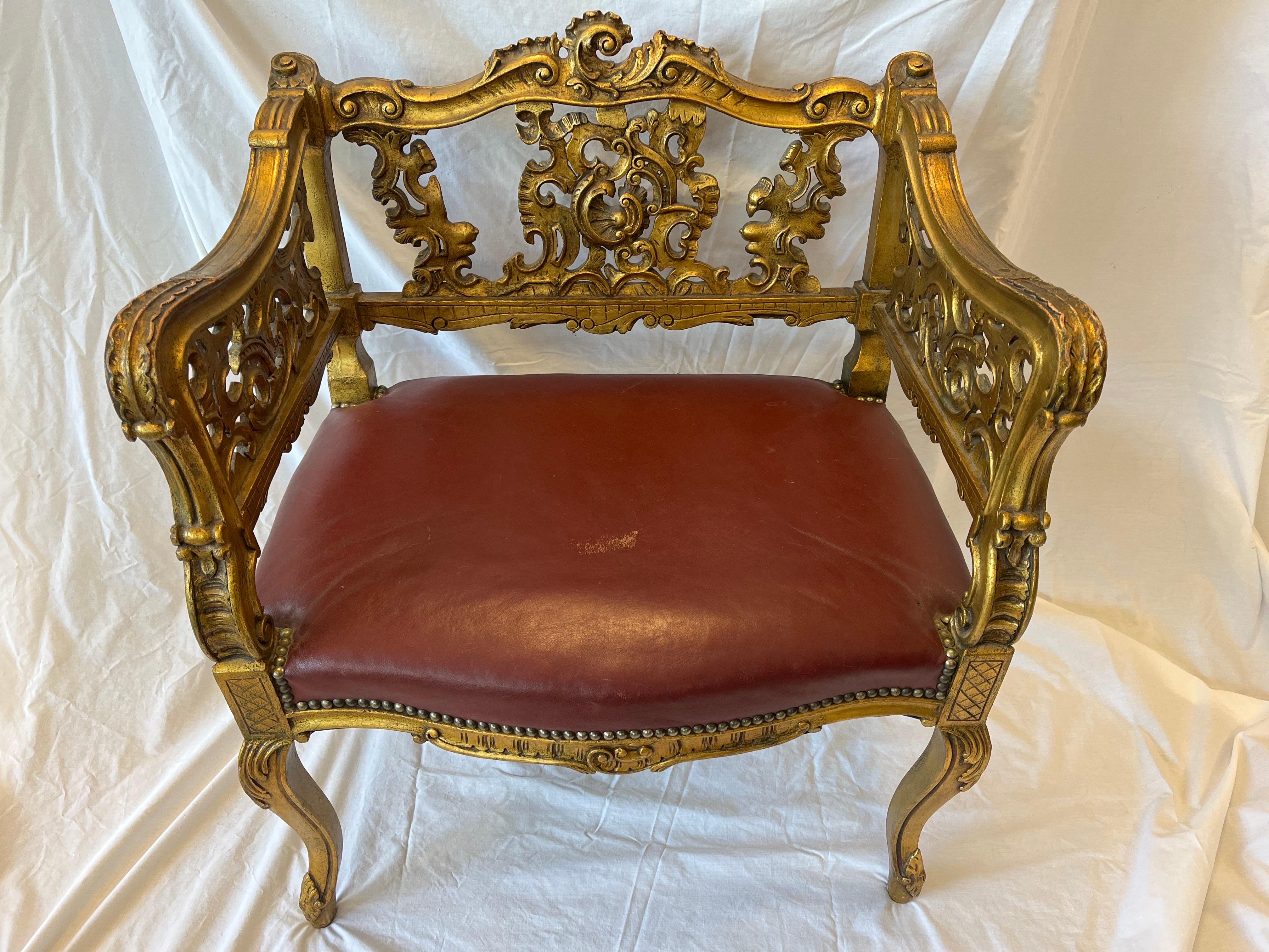 An antique, late 19th century carved and giltwood stylized armchair. The ornate Louis or Rococo style carving features ornate, scrolling designs. Cabriole legs, stylized floral motifs and cross hatching all play a part in the overall aesthetic. With