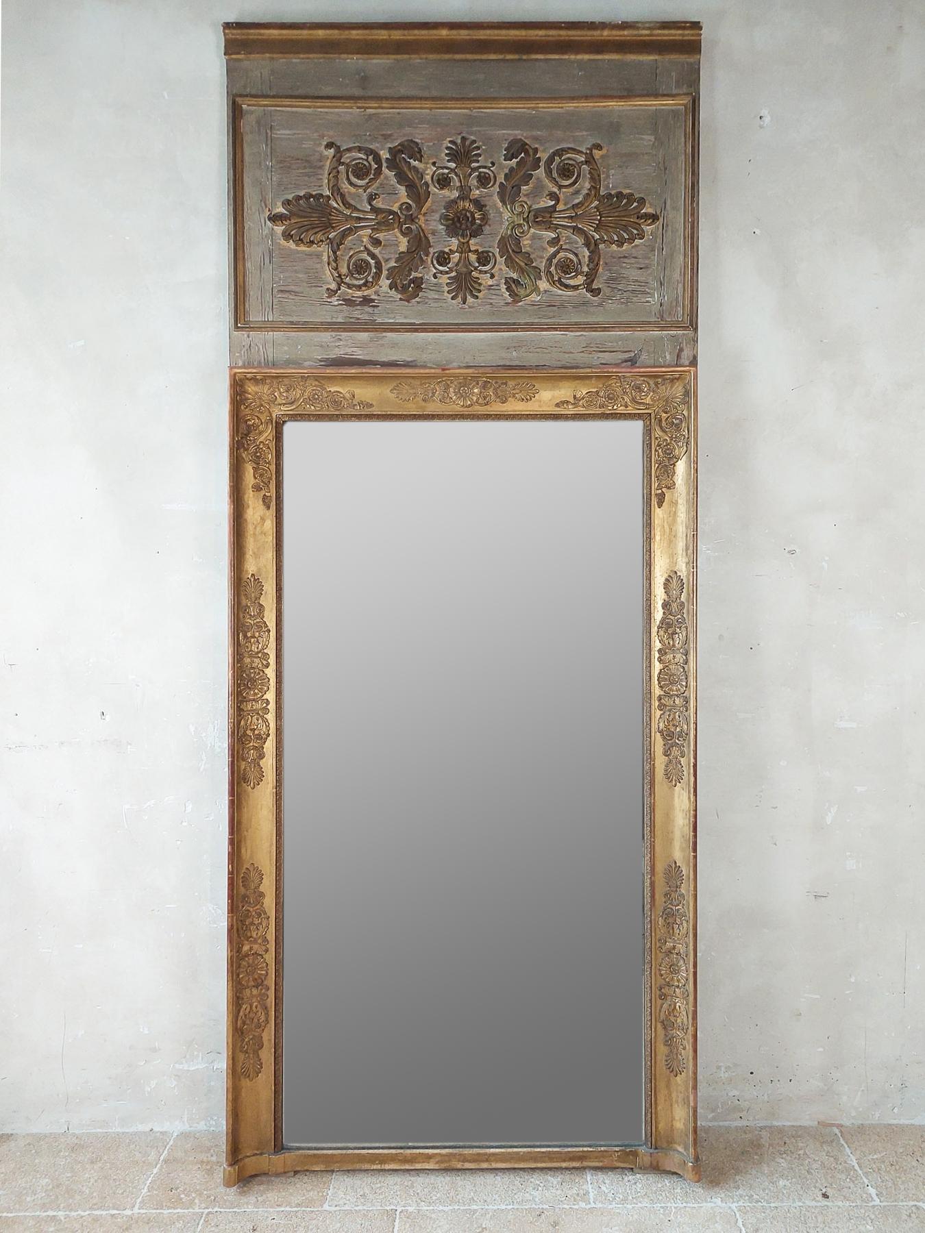 Wood carved empire trumeau mirror from ± 1800 - 1820. The gold frame of gold leaf gilded wood carving decorated with palmettes and rosettes. Trumeau mirrors were the mirrors above a fireplace in the panelling.

This antique mirror has old glass