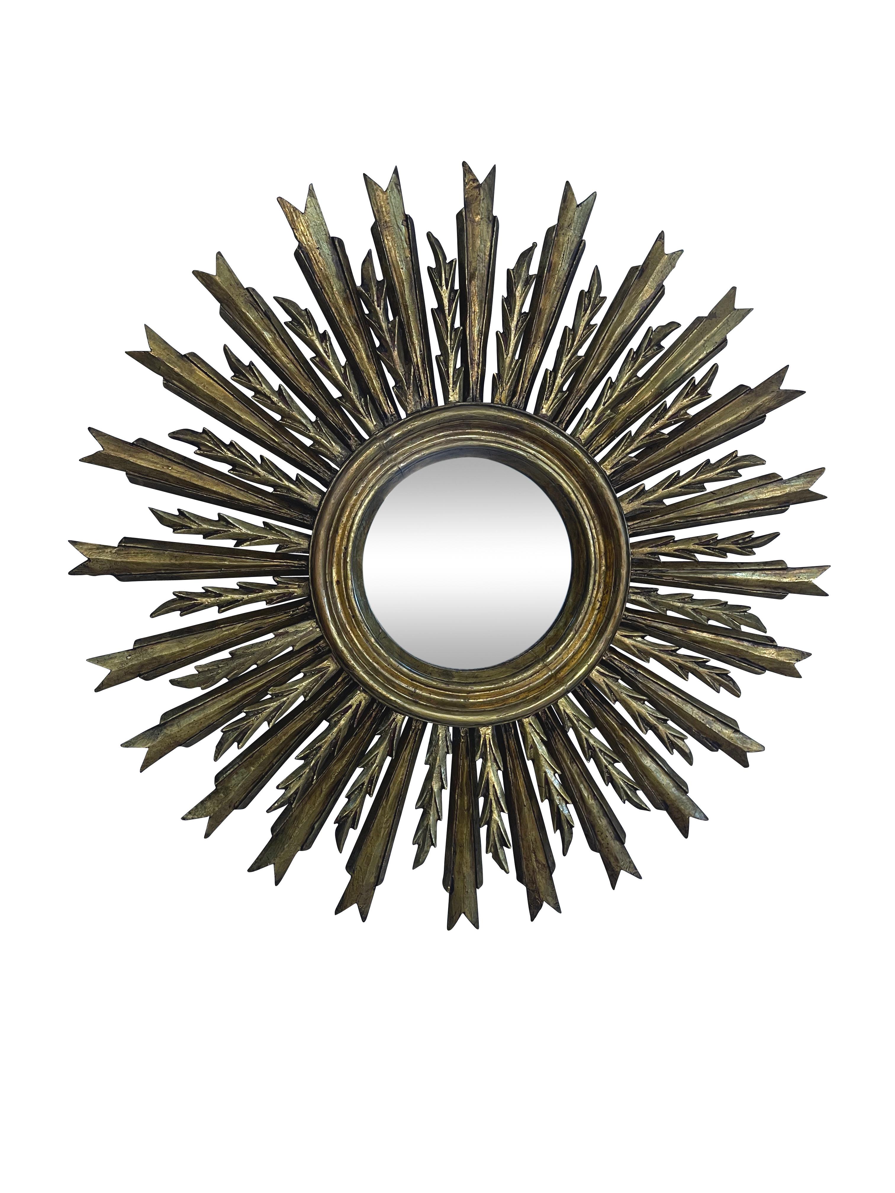 A lovely French gilt sunburst (or starburst) mirror with a double row of gilded wooden rays arranged around the original glass mirror plate's center. New glass. Beautiful aged patina and original gold leaf gilding. It will add a luxurious but strong