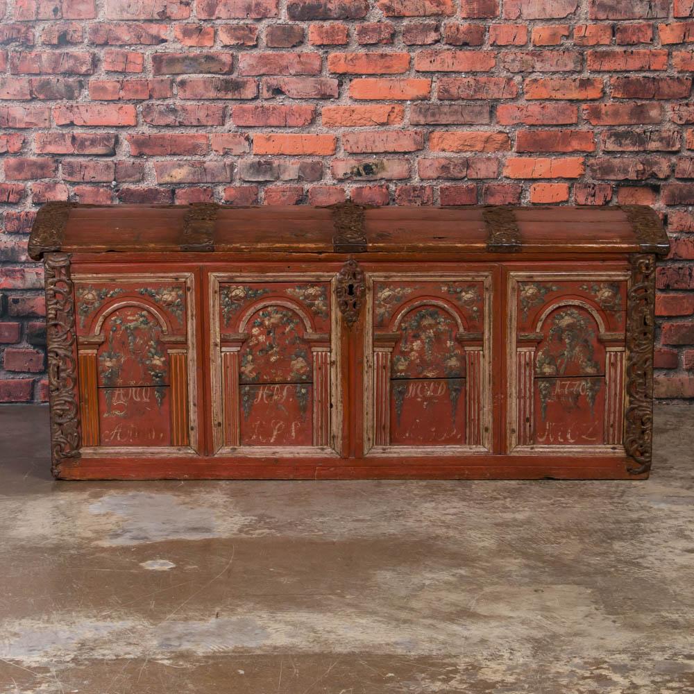 This impressive Swedish pine dome top trunk dated 1770 still maintains the beautiful original brick red paint with floral details and several monograms. Notice the and amazing hand-wrought iron features including the heavy side handles and intricate
