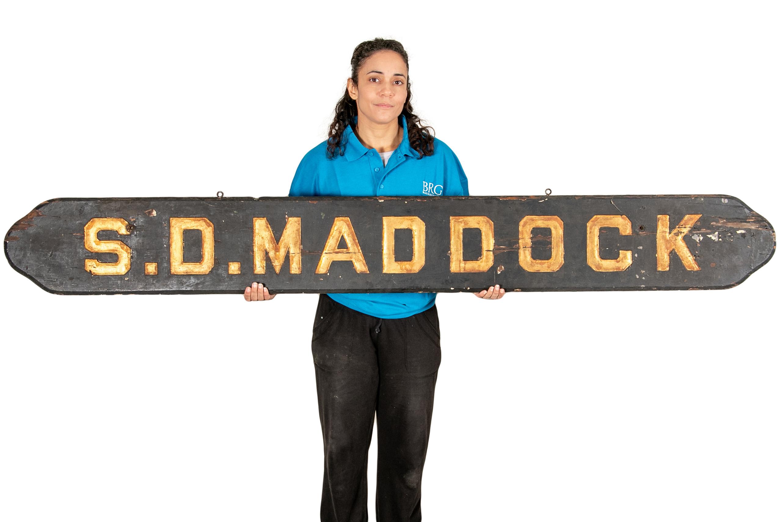 Black painted wood with rounded ends and carved and gilt letters- S.D. Maddock.

Condition: Good condition with expected signs of use including wear to the paint and gilt, chips to the front and edges- all expected when hung outside.
  