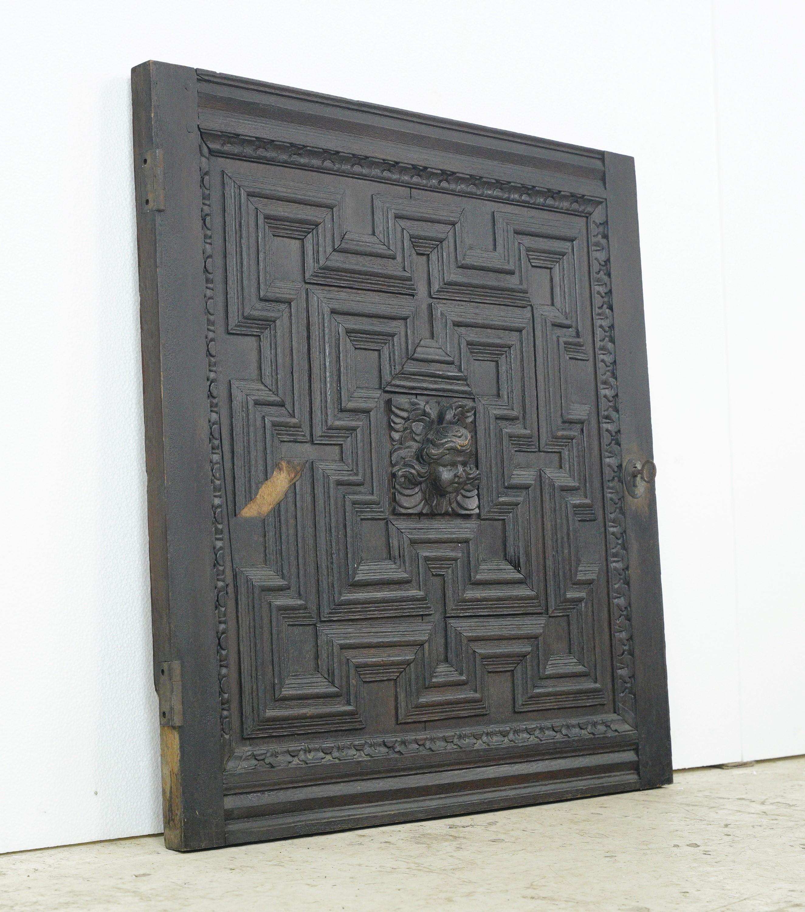 Adorn your space with this intricately carved recessed molding cabinet door with an angel relief in the center. This piece can be hung on the wall as is or attached to a cabinet. This is in good condition, with minor wear. The key is included to