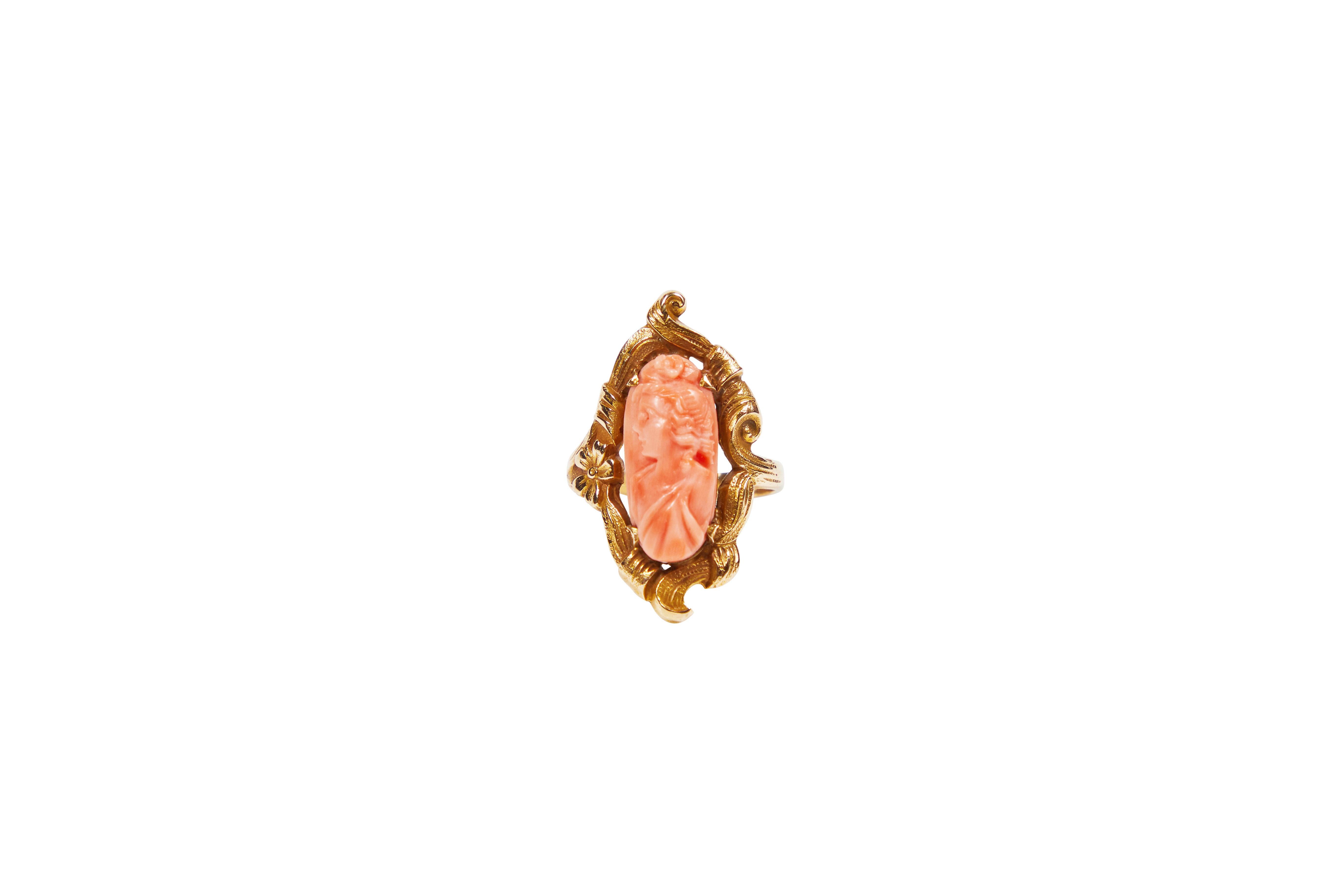 Antique carved angel skin coral elongated oval cameo ring with an decorative setting set in 10KT (c 1920). Carving is of maiden in toga with hair in topknot. Size 6.


