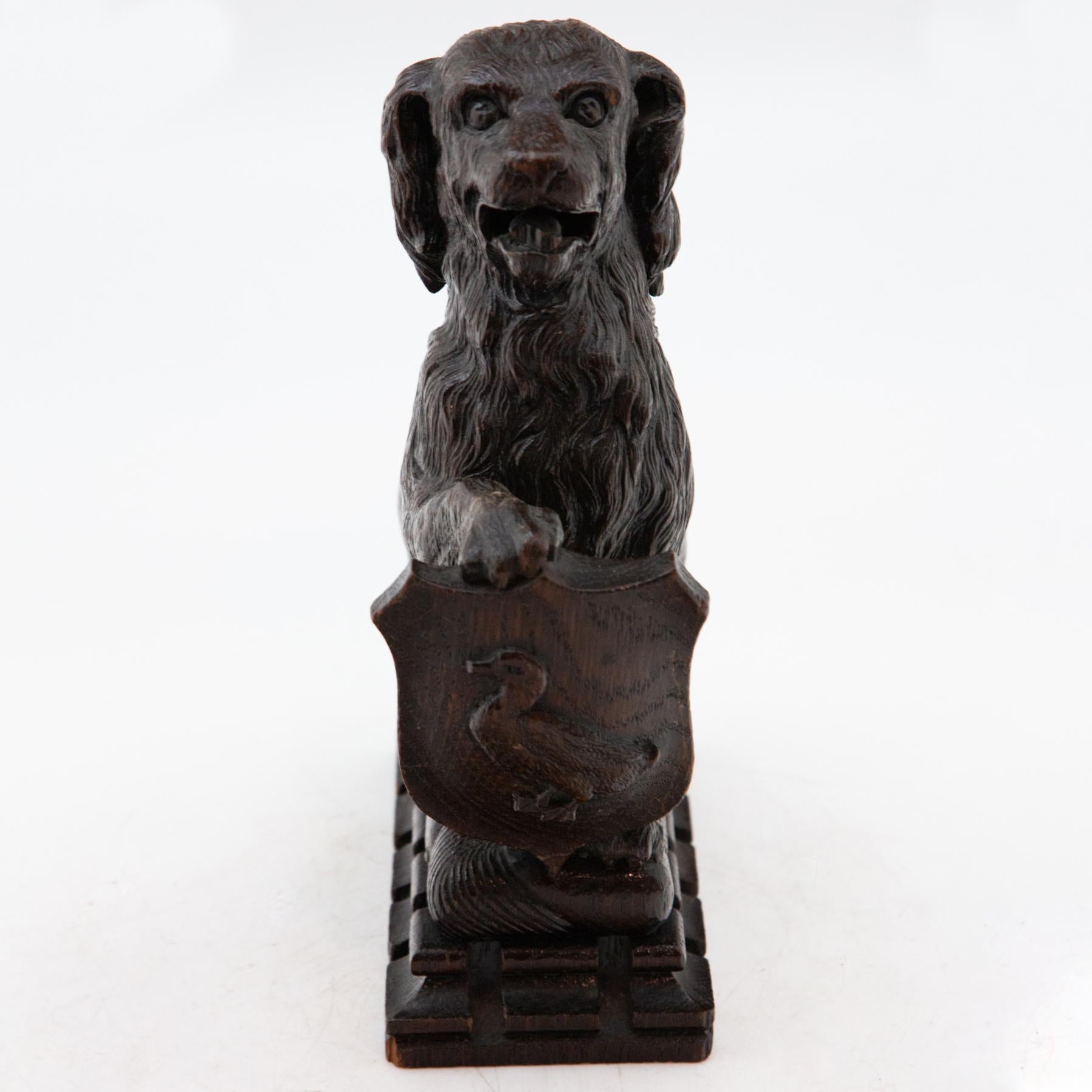 Antique carved Black Forest dog holding duck crest. Measures: 9