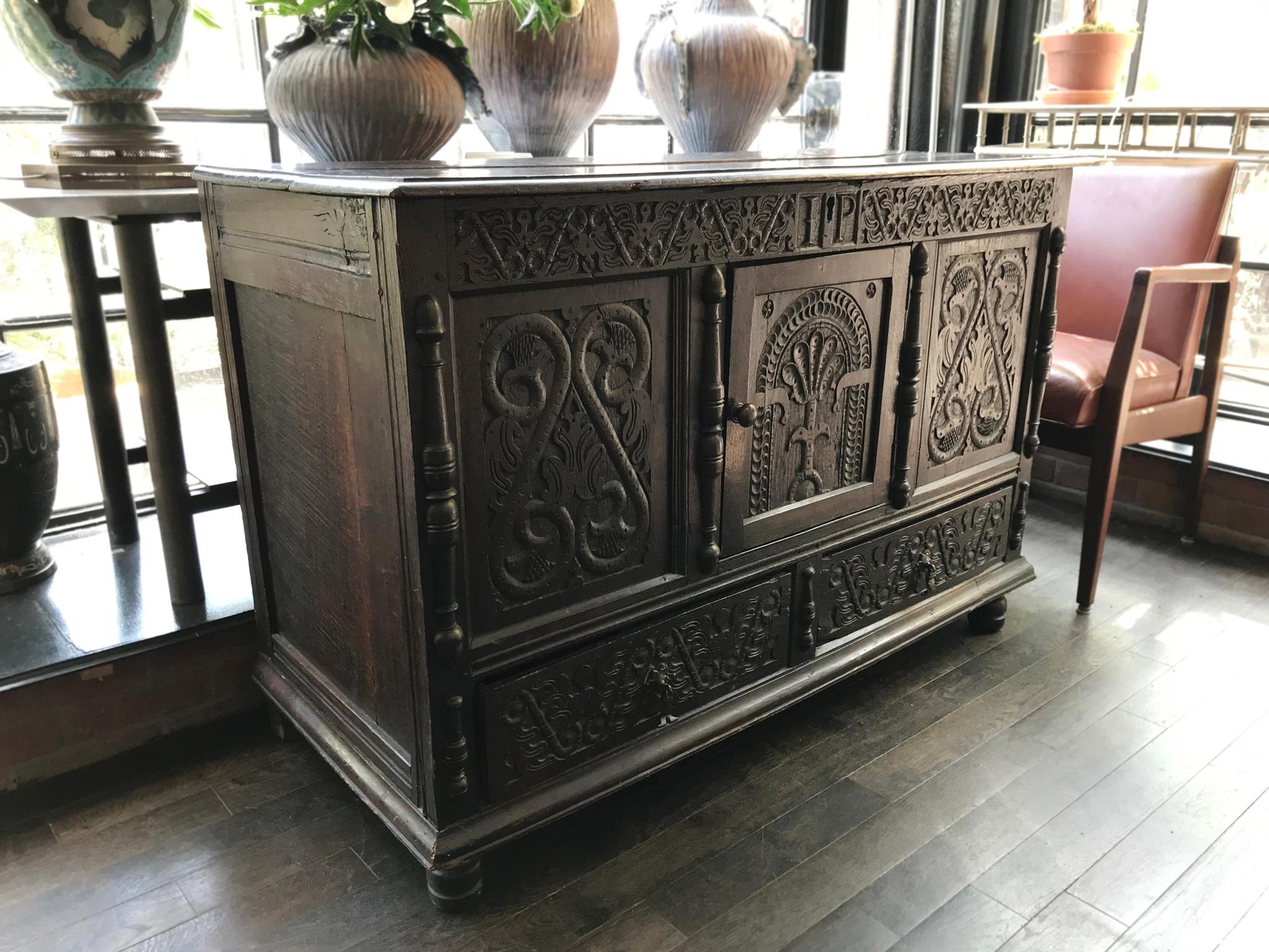 An exquisite, antique cabinet-chest or Pilgrim's trunk, circa 17th-18th century. It is comprised of black oak. The decorative elements are beautifully carved on the front door and drawers. These include ornate floral and arboreal patterns framed by