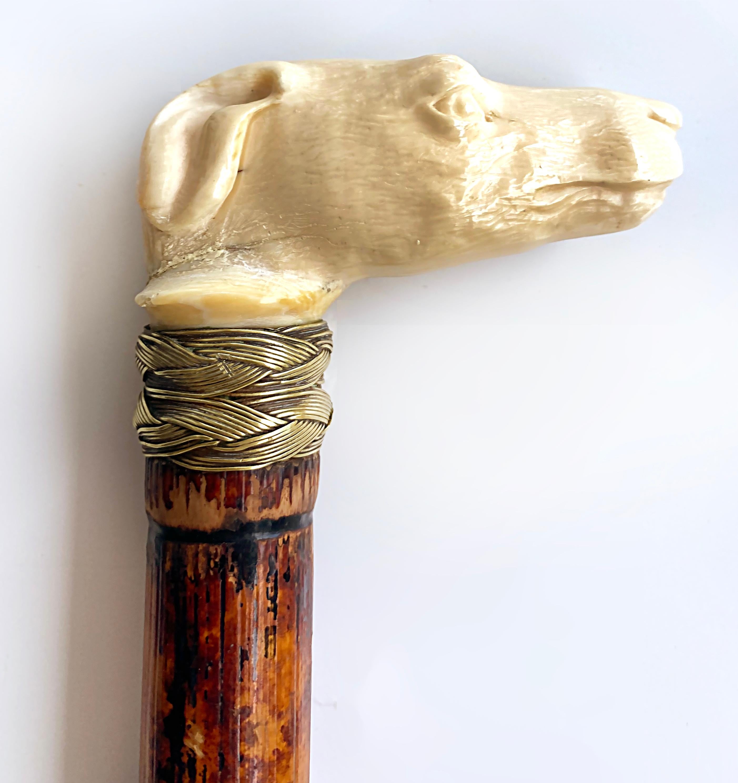 Antique Carved Bone Greyhound Dog Bamboo Walking Stick with Braided Banding

Offered for sale is an antique late 19th-century hand-carved greyhound head handled walking stick with braided brass metal banding. The cane shaft is a burned-finished
