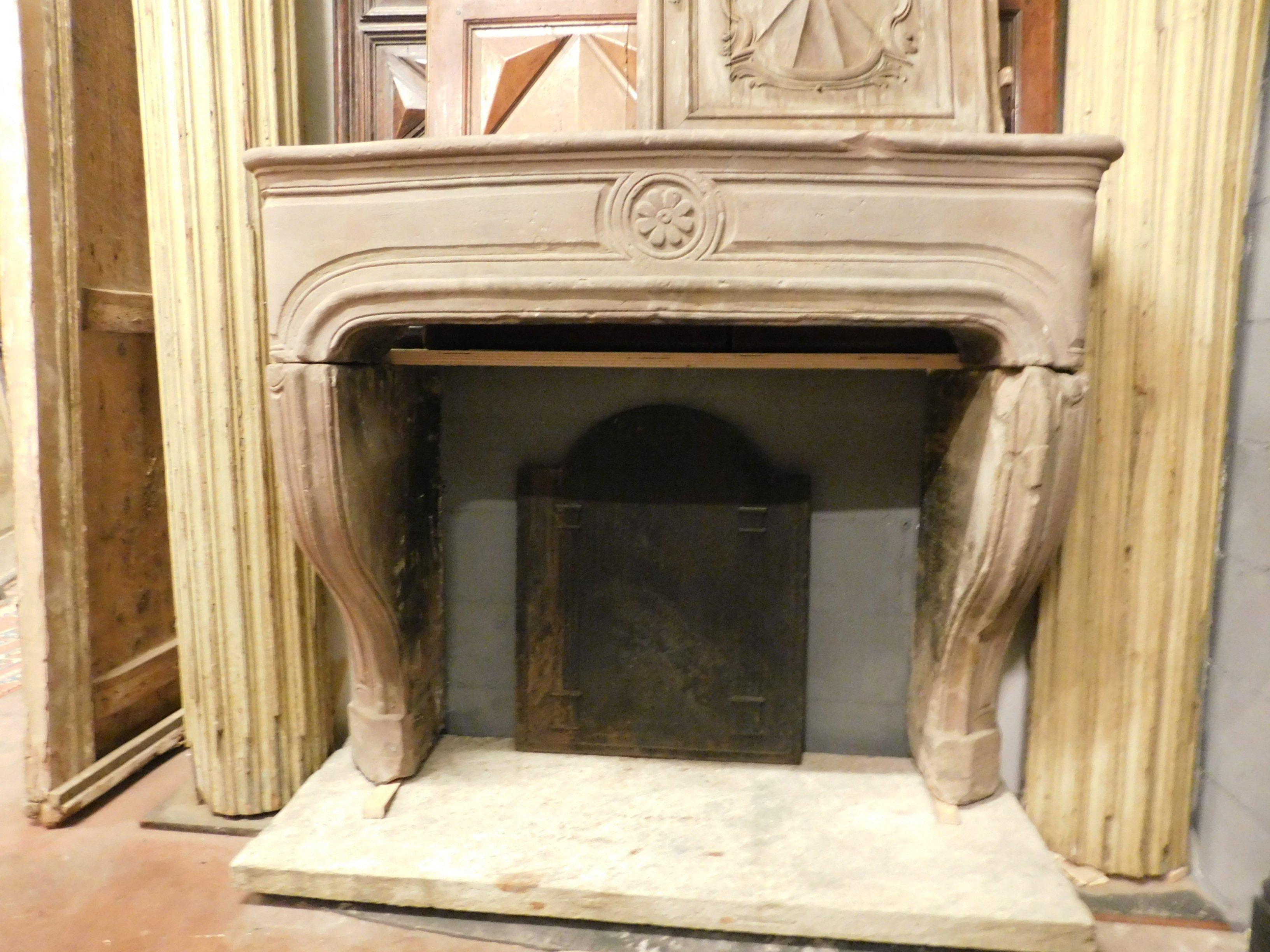 Antique Burgundy stone fireplace, all along its line with central flower, beautiful convex and rounded shape on the front, wavy and protruding legs, entirely hand carved in French stone with a tendency to pink, handmade in the early 18th century,