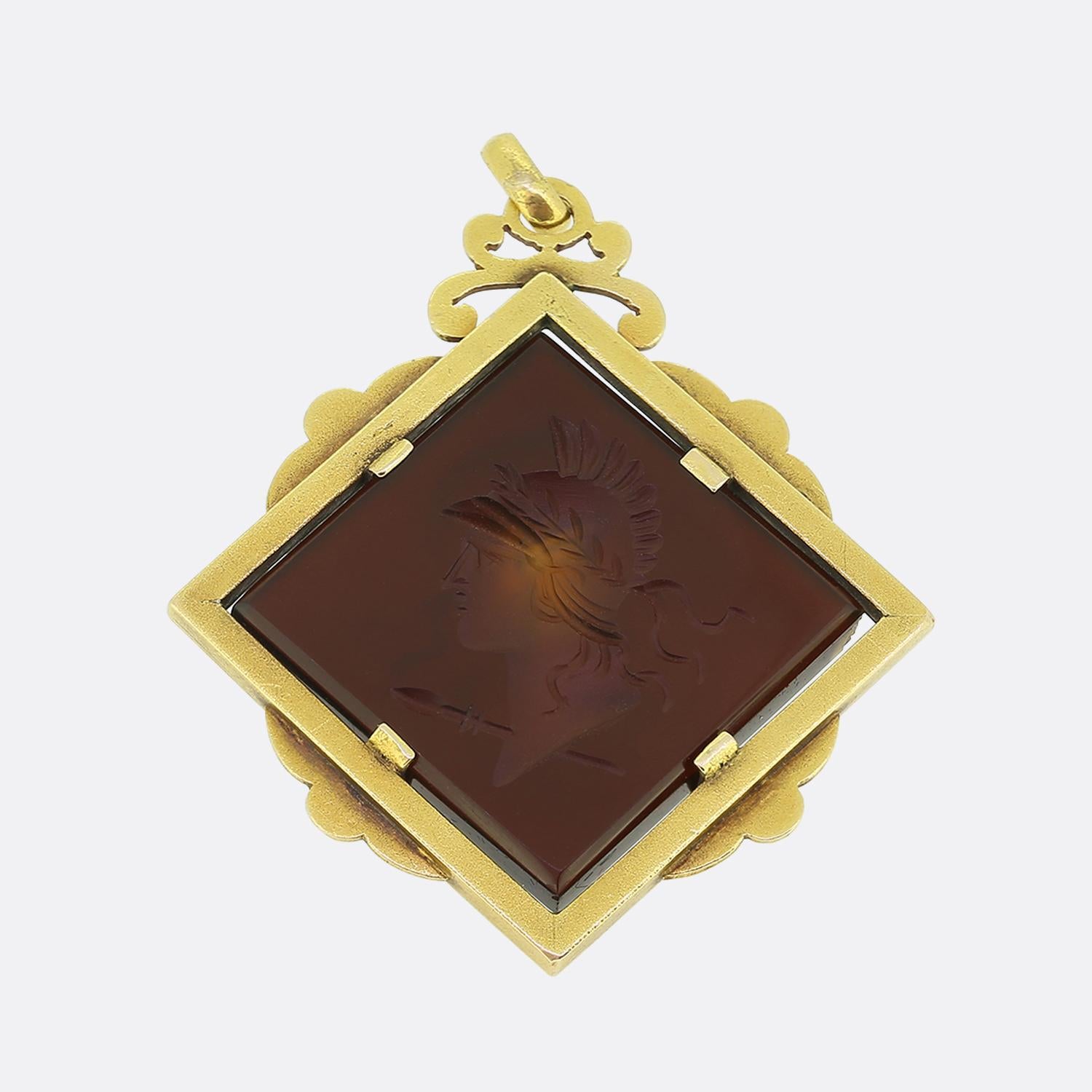 Hier haben wir einen auffälligen Anhänger mit einem detaillierten Karneol-Intaglio. Das Schmuckstück ist in einen Rahmen aus 18-karätigem Gelbgold gefasst, der mit seinen geschwungenen Verzierungen am äußeren Rand viktorianische Handwerkskunst
