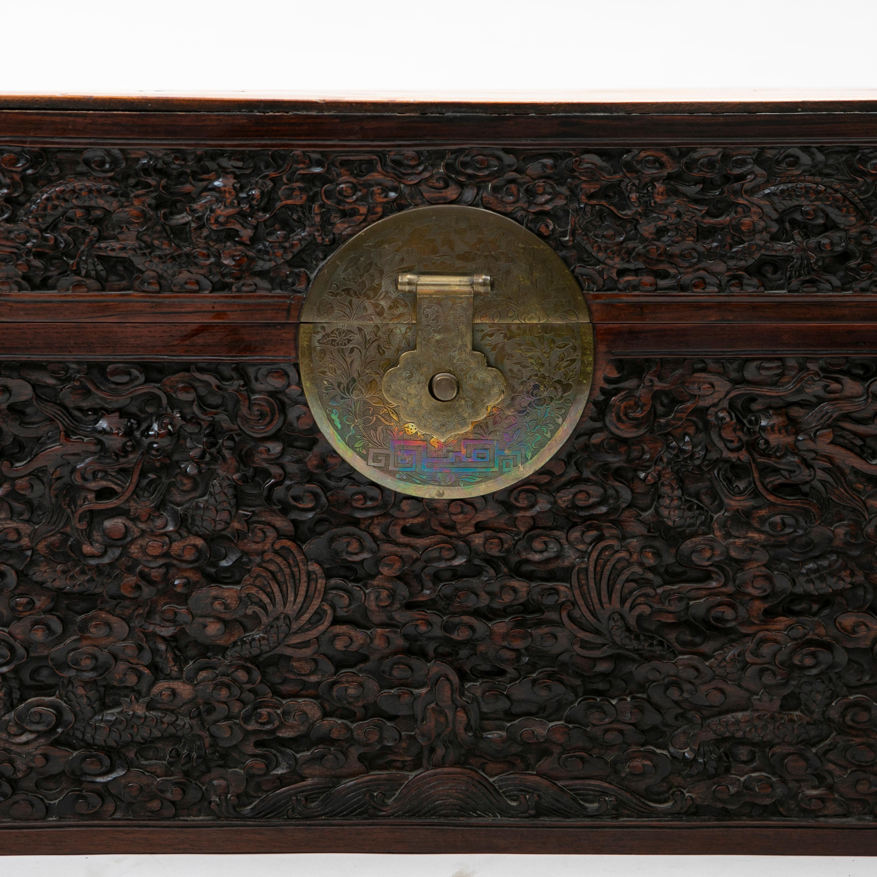 Coffre chinois ancien sculpté en camphre et bois noir.
Façade en bois noir sculpté en relief de dragons dans le ciel / les nuages.
Muni d'un médaillon d'origine en laiton, richement ciselé en forme de fleurs et de feuillages.

État d'origine
