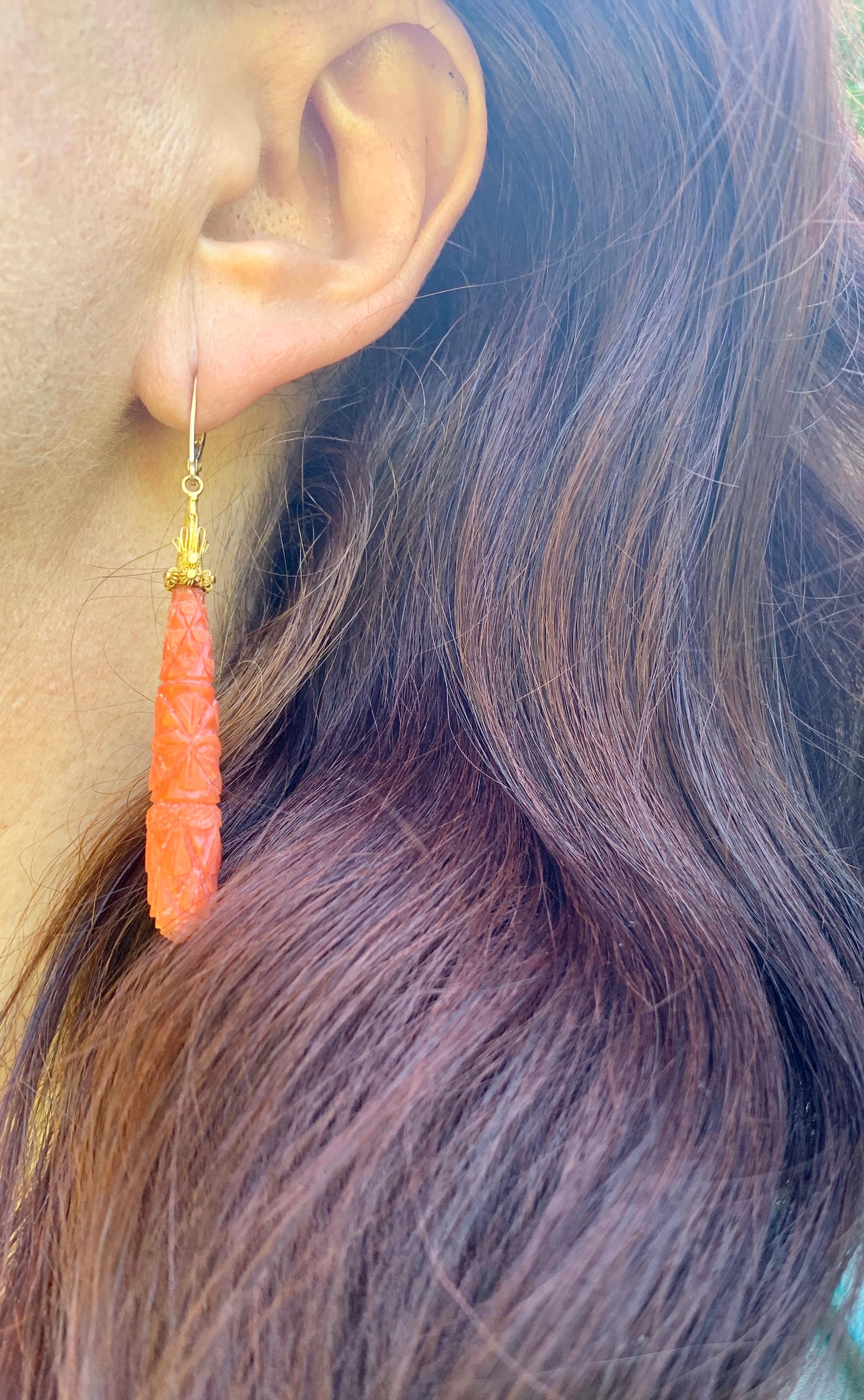 Very fine quality Etruscan Revival carved coral and 18K yellow gold earrings, The cone shaped gold fittings embellished with intricate floral elements and a central shell design composed of fine wire goldwork, mounted with elongated beautiful coral
