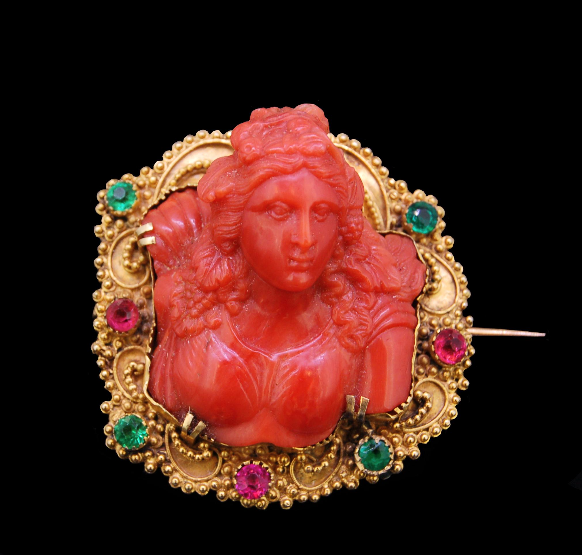 IMPORTANT ANTIQUE CARVED CORAL CAMEO BROOCH, the carving in high relief of a woman's bust. The mount set with green and red stones and decorated with granulation balls. Cameo probably 17th/18th century. L. 4.3 cm. H. cameo relief 1.9 cm. 15.7 grams.