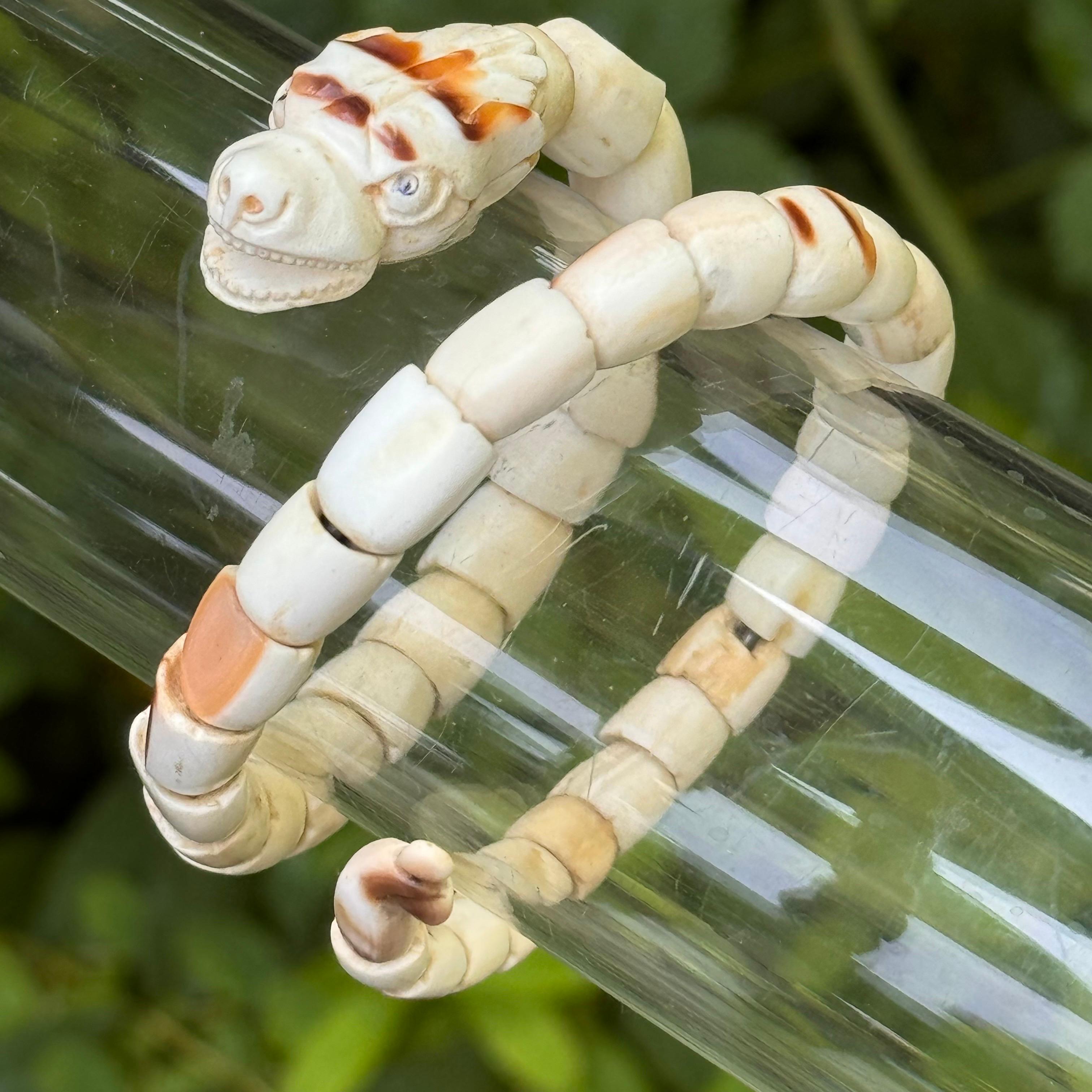 Exquisita antigüedad  La pulsera lleva coral blanco pálido, hábilmente tallado en forma de serpiente enroscada. La pulsera envuelve naturalmente la muñeca con cuentas que forman los segmentos de la serpiente. La cabeza de la serpiente también está