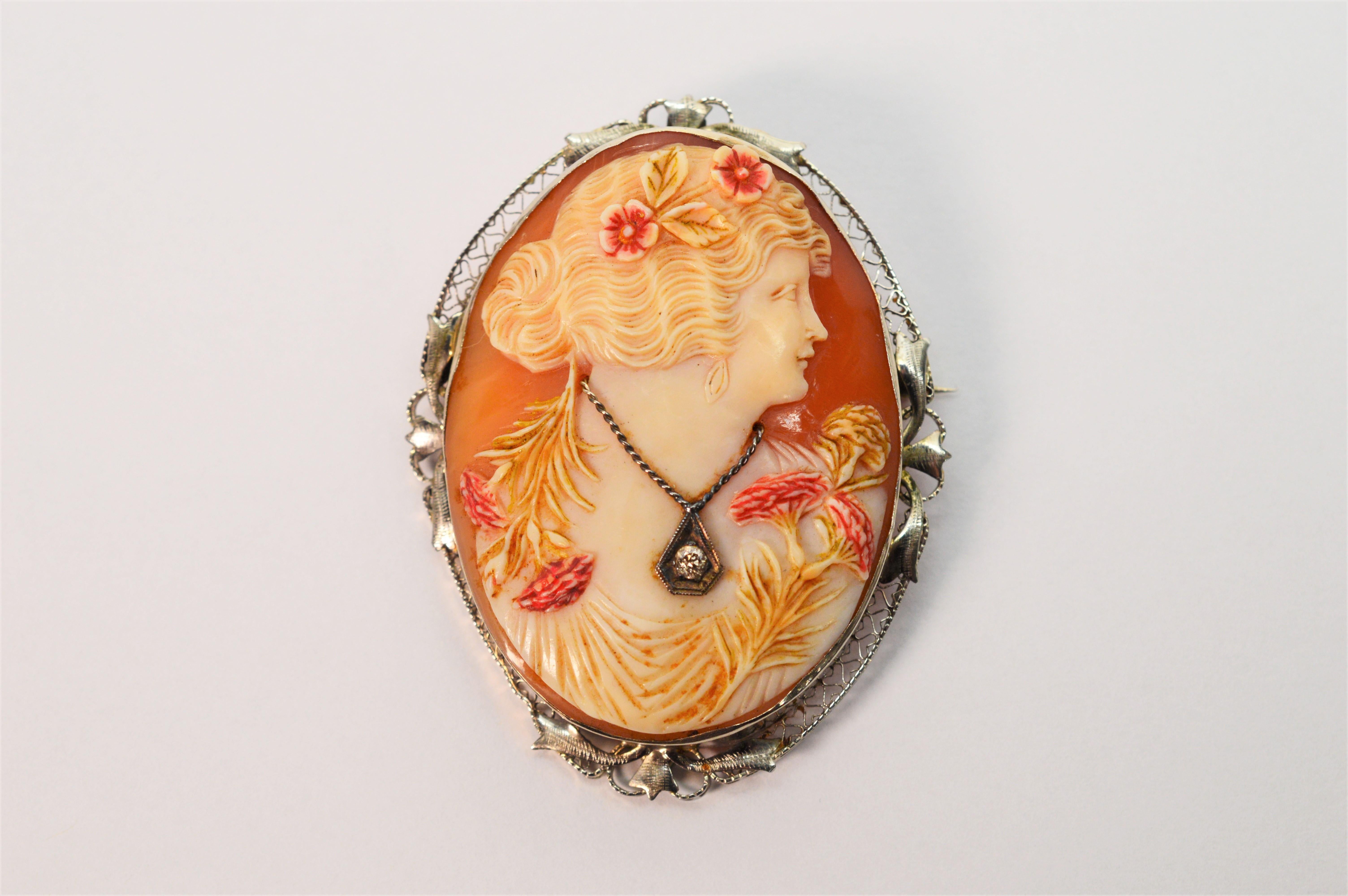 This elegant lady poses proudly in her finery with flowers in her hair and a jewel gracefully draping the neckline. Finely hand carved relief in cornelian shell, the notable floral details are delicately enhanced by hand painted accents. A diamond