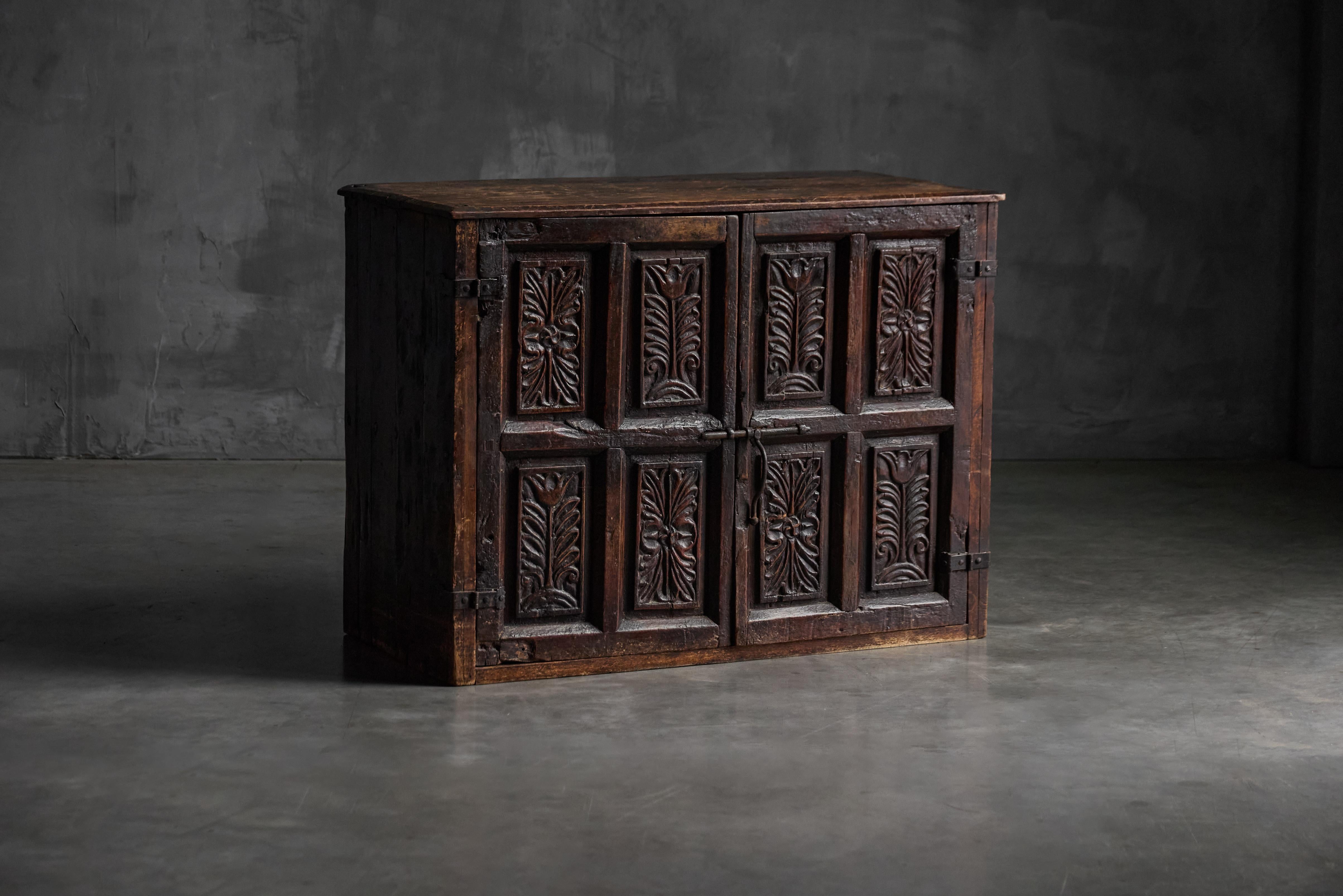 Cette armoire à deux portes finement sculptée provient du Pays basque français et date d'environ 1800. Fabriqué en bois massif foncé, il présente des panneaux profondément sculptés avec des motifs de feuillage typiques de l'artisanat régional de