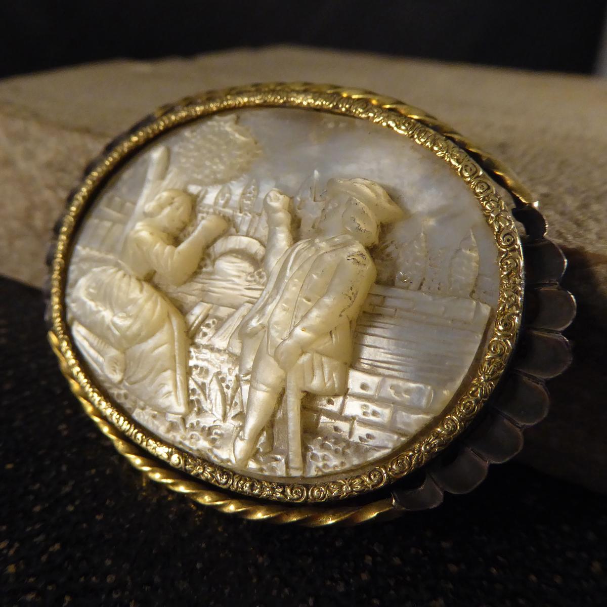 Such an exquisitely detailed carved Mother of Pearl, showing a scene between a man and women. The surround of the Mother of Pearl is intricate design in Gold with a Gold and Silver halo to accompany. This 17th Century carving looks to have