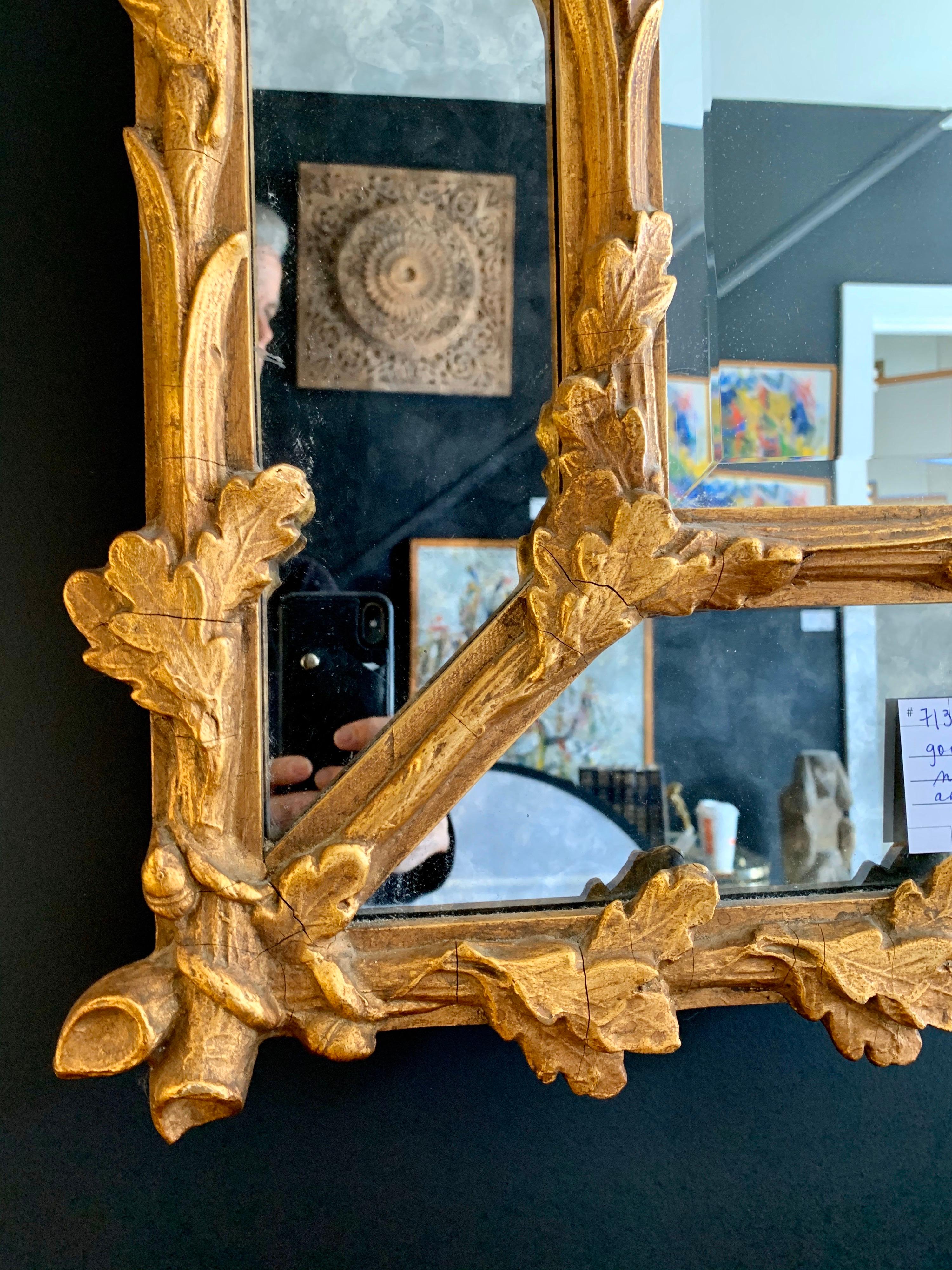 A very fine Florentine giltwood carved mirror framed with carved branches of oak leaves and acorns scrolled on borders and centered with a beveled mirror plate and a border of smoked glass. Quite stunning, indeed.