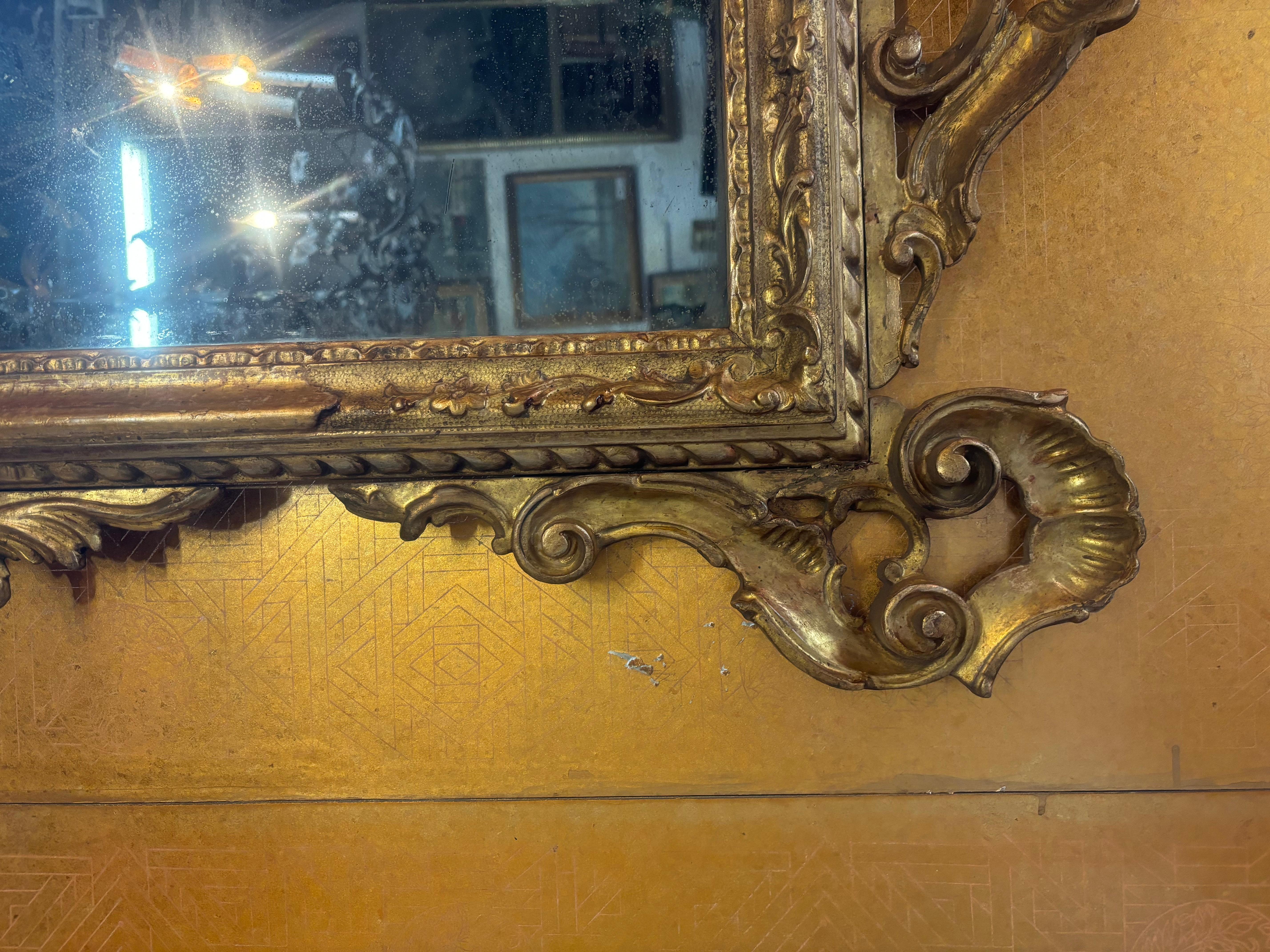  This finely carved mirror has original mirror plates and is sumptuously adorned with scrolled foliate and garlands. At the top is a mirror amidst scrolled giltwood.