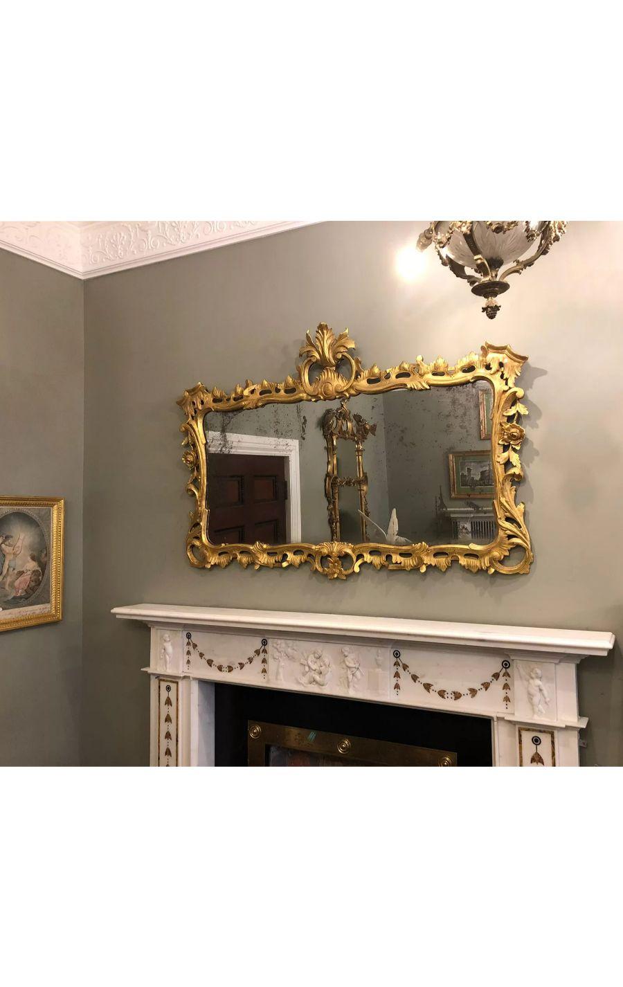 Miroir ancien en bois sculpté et doré de style rococo.

Le cadre en bois doré, exubérément sculpté à la manière rococo, avec des acanthes, des feuillages et des rinceaux.

Une forme idéale pour le dessus d'une cheminée ou d'une table