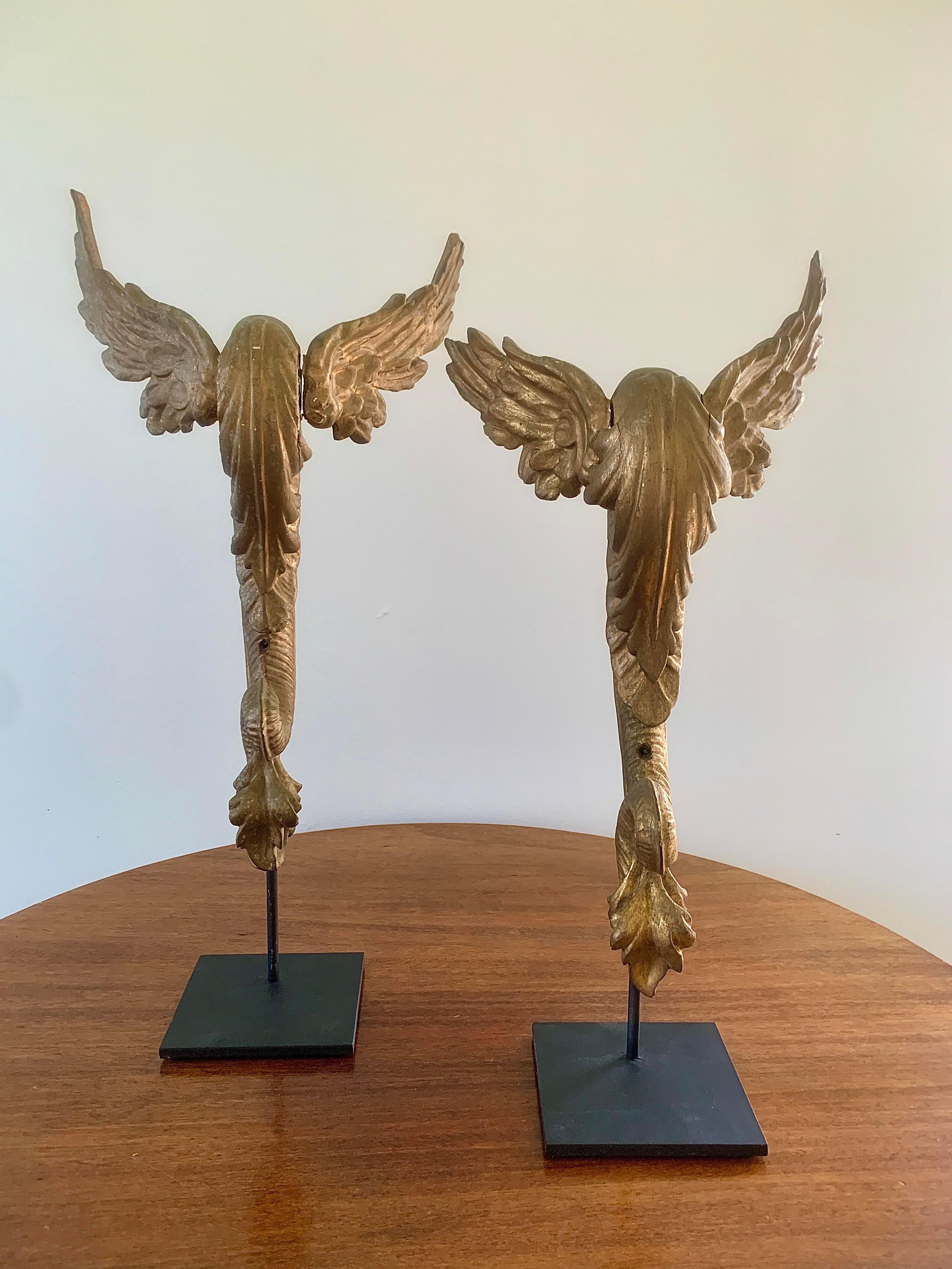A stunning and rare pair of antique architectural fragments with wings and serpents' tails

French or Italian, circa late 18th century.

Carved gilt wood, on custom made black steel mounts.

Measures: Tall: 8.75