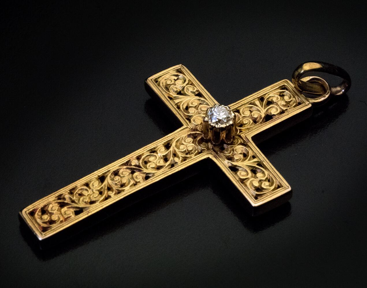 Circa 1880

The 14K gold cross is finely carved with a medieval style scrolling floral design and centered with a sparkling old mine cut diamond (approximately 0.10 ct)

Total length of the cross with suspension ring is 40 mm (1 5/8 in.), width is