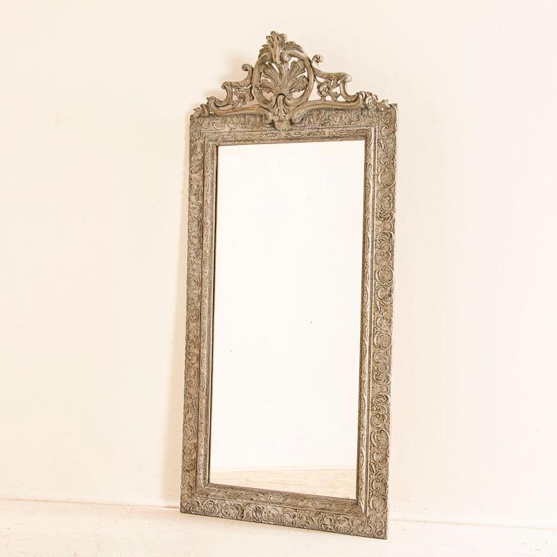 This exquisite mirror has detailed carving along the frame and lovley crown. Enlarge photos to appreciate the gold burnish accent to the gray painted finish which adds a soft depth to it as well. The frame shows minor age related cracks typical in