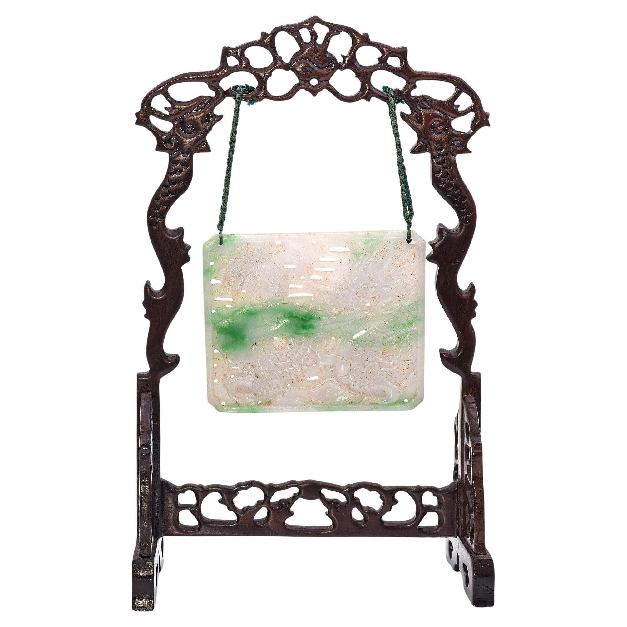 Figurilla antigua tallada en jade verde y blanco que cuelga de un soporte de madera