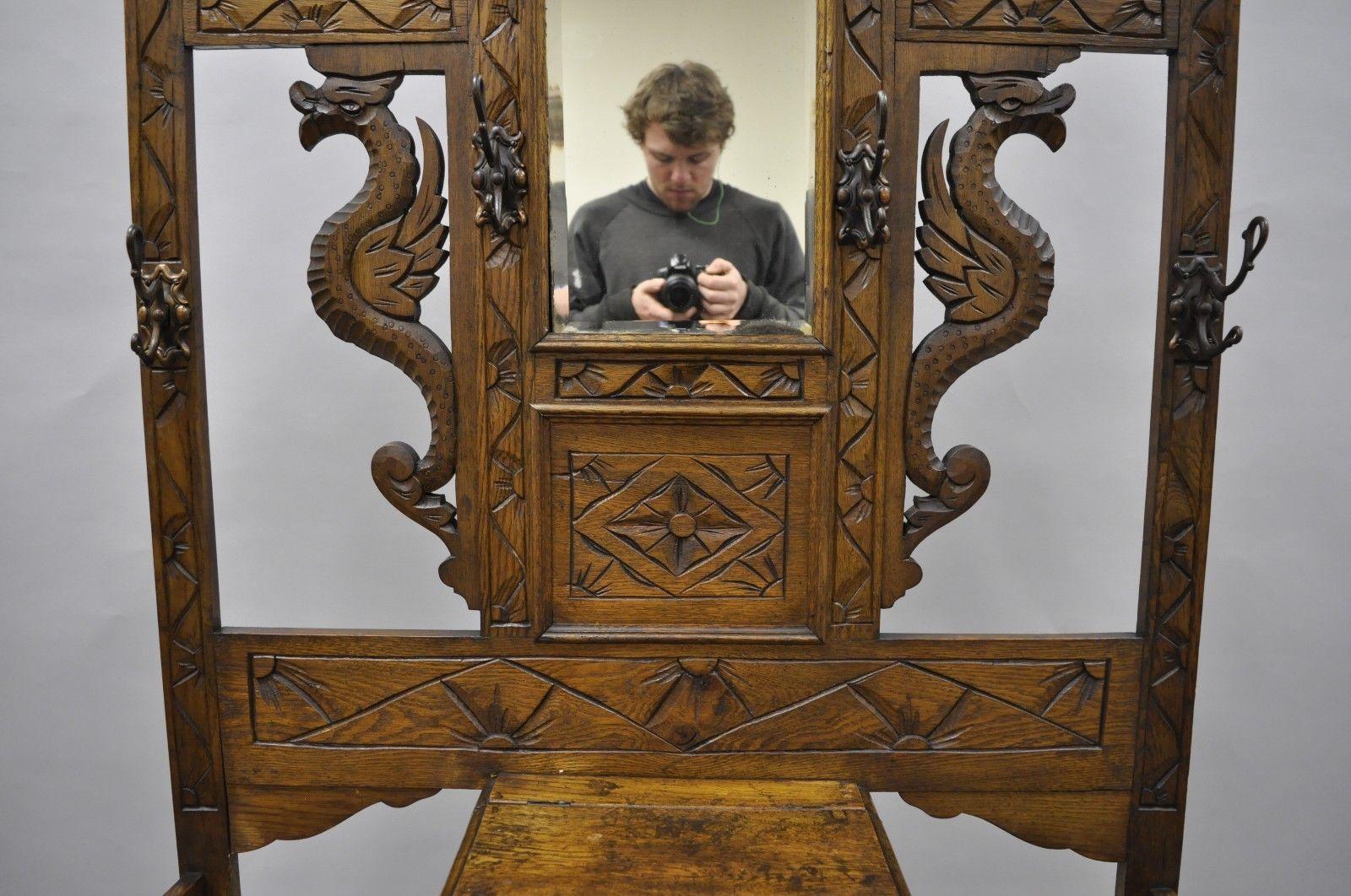 Antique carved griffin oak Jacobean Renaissance coat / umbrella stand. Item features solid wood construction, carved griffin figures, carved face on top rail, 6 metal hooks, beautiful wood grain and warm patina, and beveled glass mirror, circa 1900,
