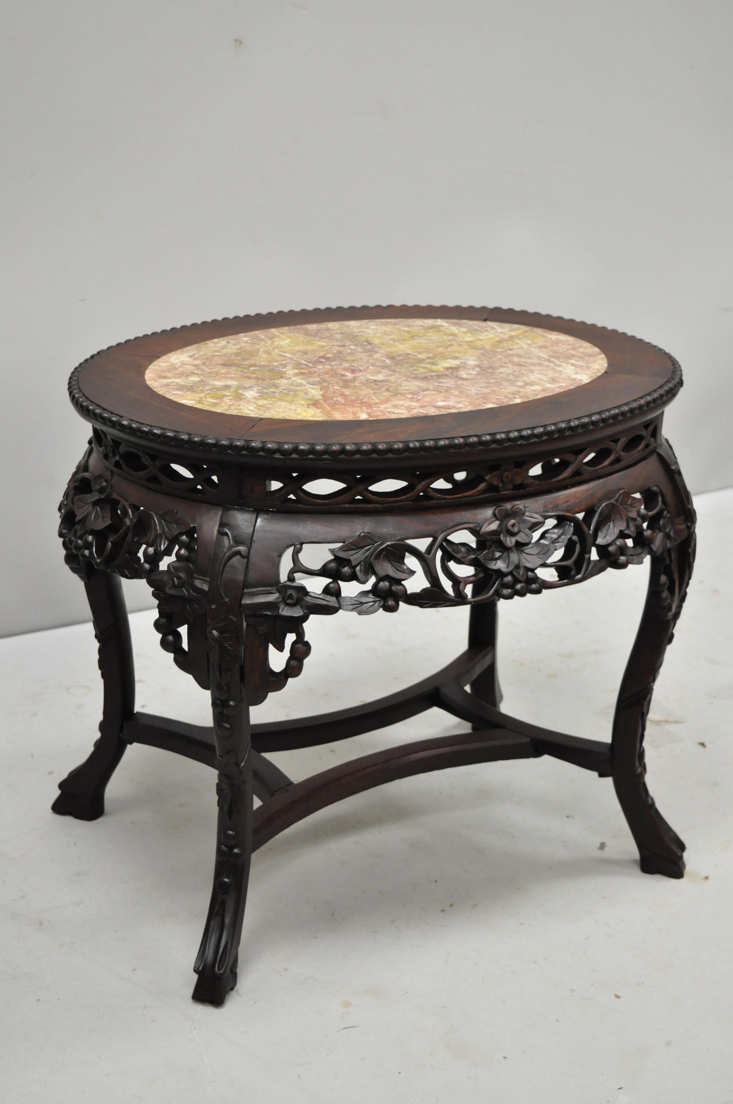 Antique carved hardwood rosewood and marble oval top Chinese coffee table (F). Item features inset marble top, pierce carved floral skirt, carved stretcher base, solid wood construction, finely carved details, very nice antique item, circa late