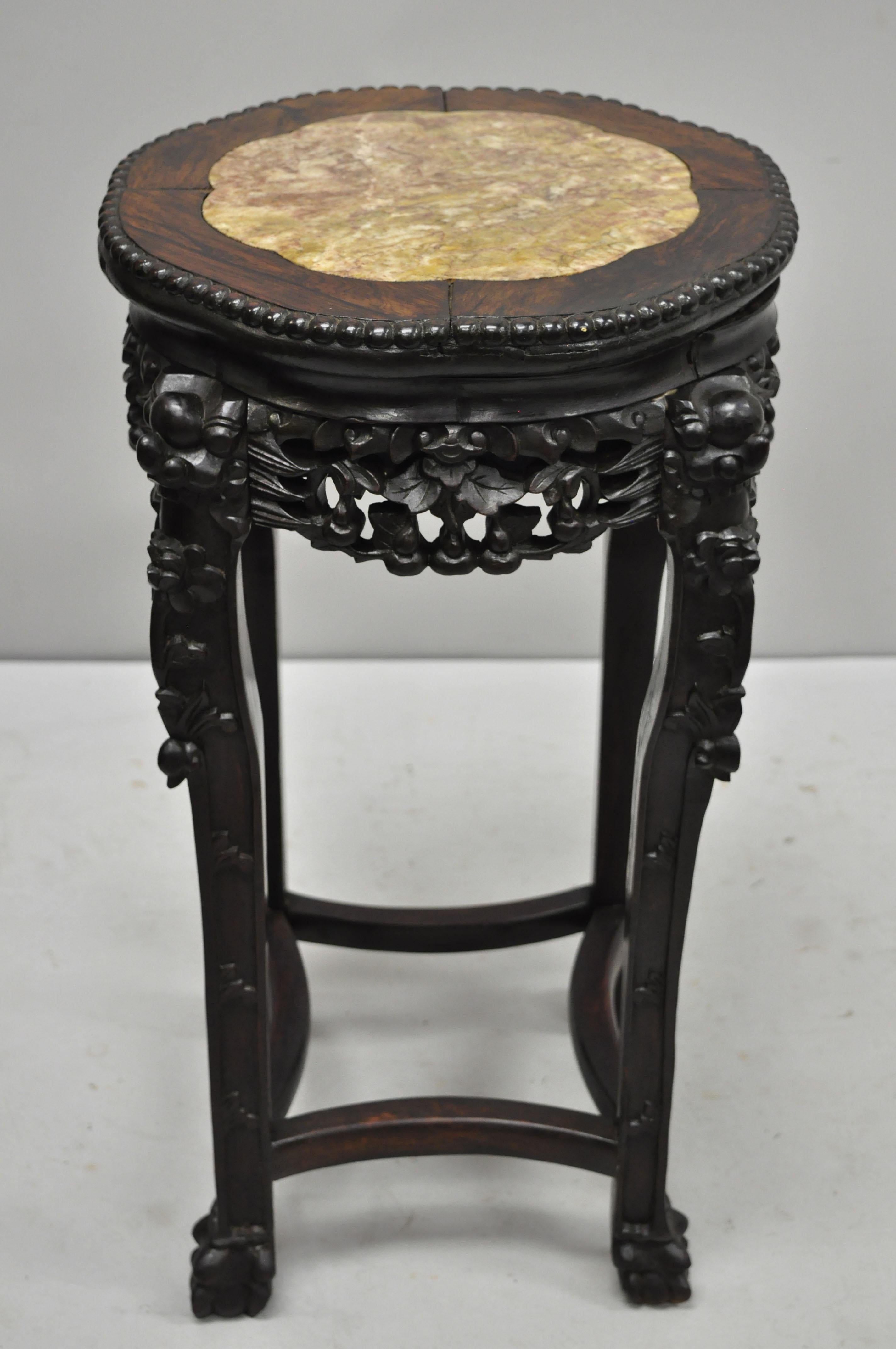 Antique carved hardwood rosewood and marble-top Chinese pedestal table (C). Item features inset marble top, pierce carved floral skirt, carved stretcher base, solid wood construction, finely carved details, very nice antique item, circa late