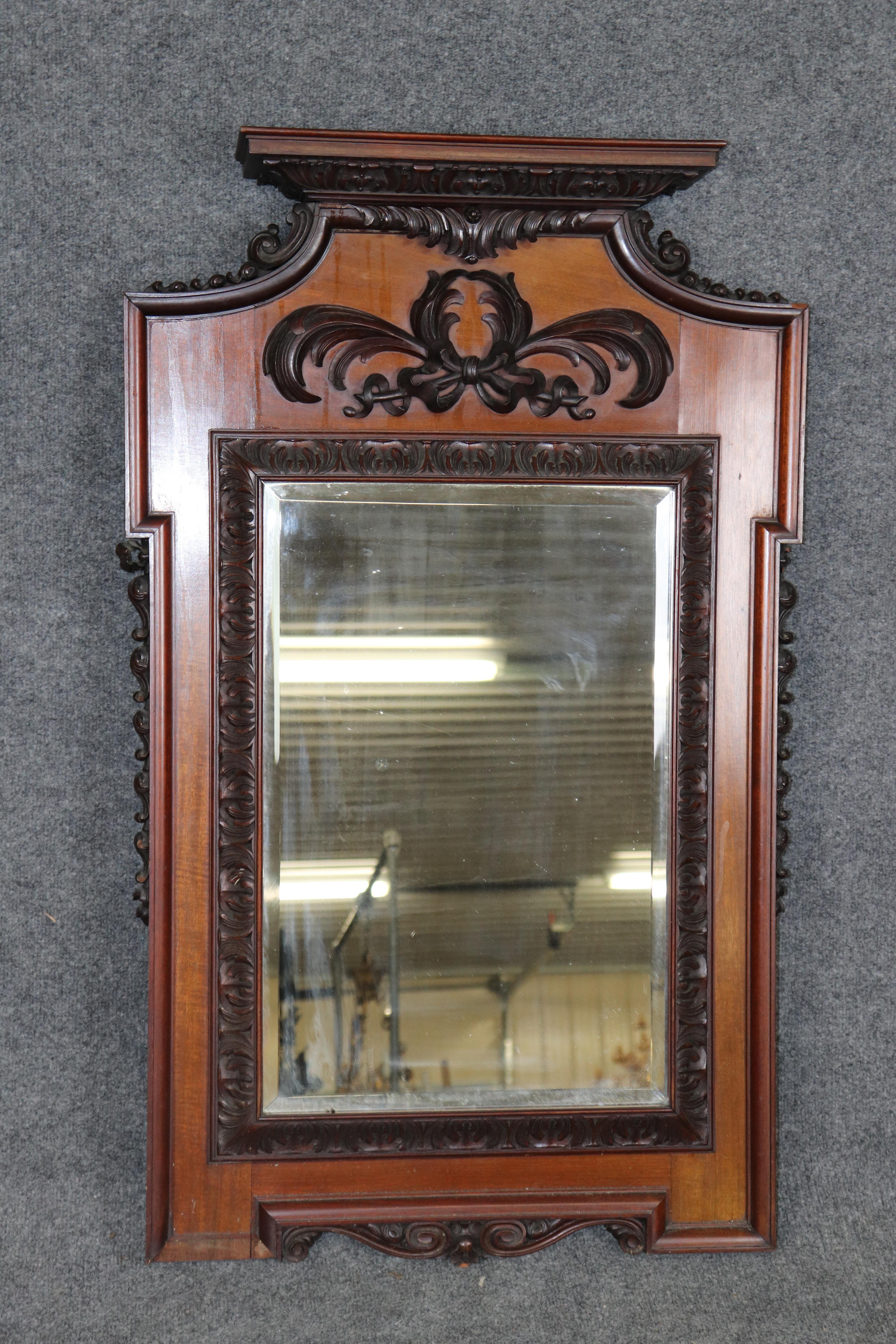 Dimensions - H: 41 1/4 in W: 25 1/2 in D: 4 1/4 in 

A striking Antique Italian wall mirror, exquisitely hand-carved from rich mahogany, dating from the late 19th to early 20th century. This elegant mirror captures the timeless artistry of Italian